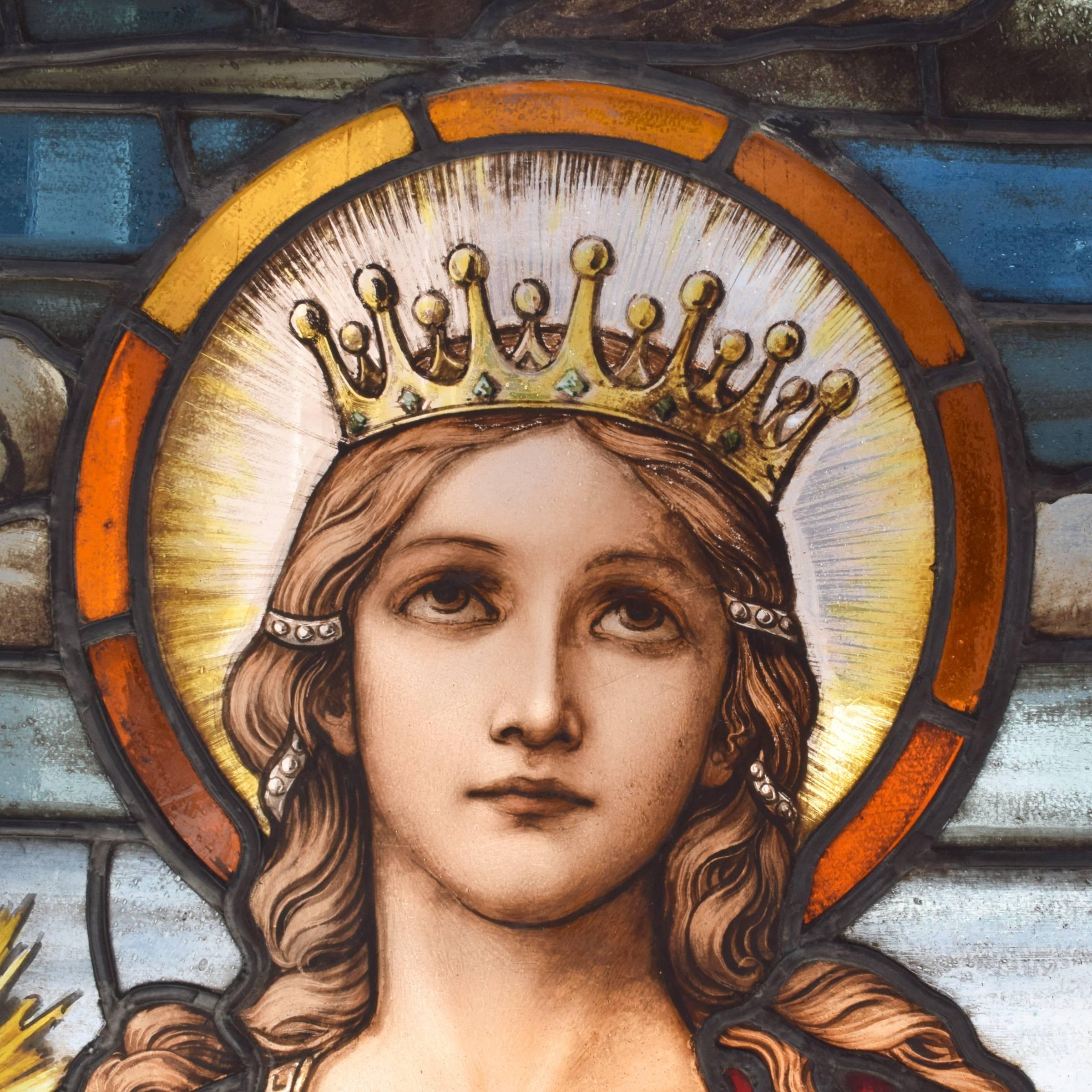 A fantastic art glass scenic arch top window from an American church. The window depicts St. Barbara, the patron saint of artillerymen, standing under a stormy sky with a tower in the distance. She’s wearing a crown and holding a sword and palm