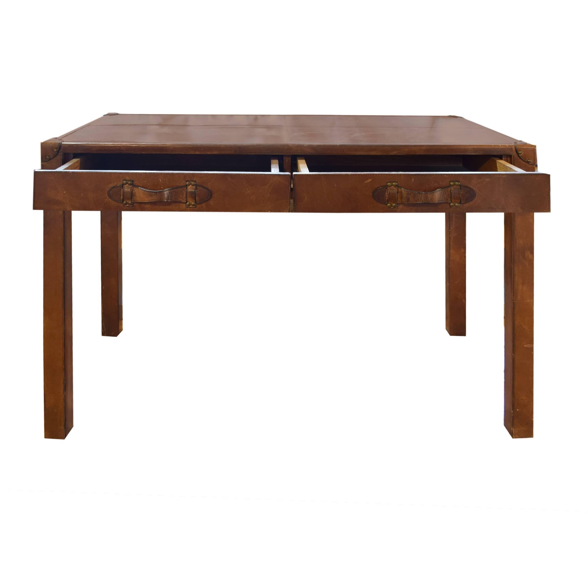 A stylish rectangular Mid-Century leather-clad desk having two large central drawers, raised on four rectangular legs.