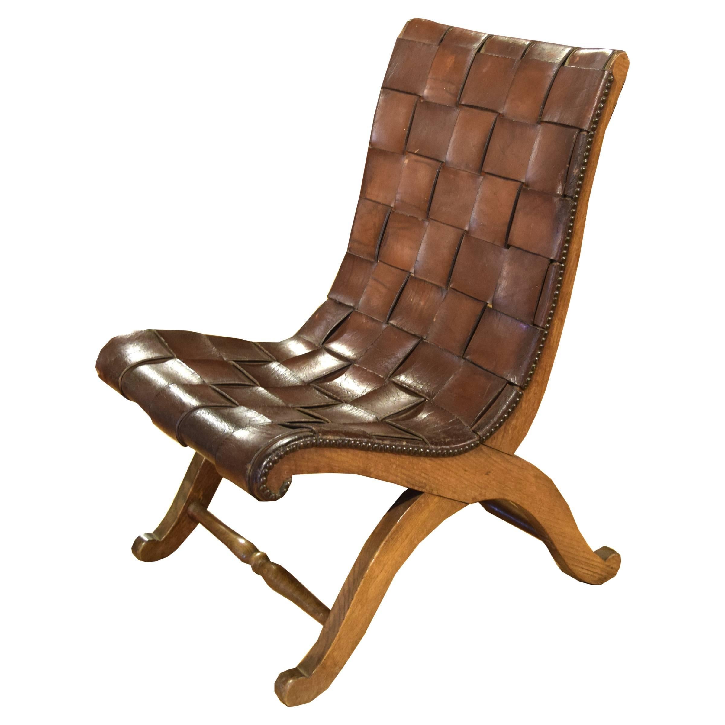 A French side chair having a rich brown woven leather back and seat atop a wooden frame with sinuous curved legs and turned stretchers, with a great patina, circa 1920.