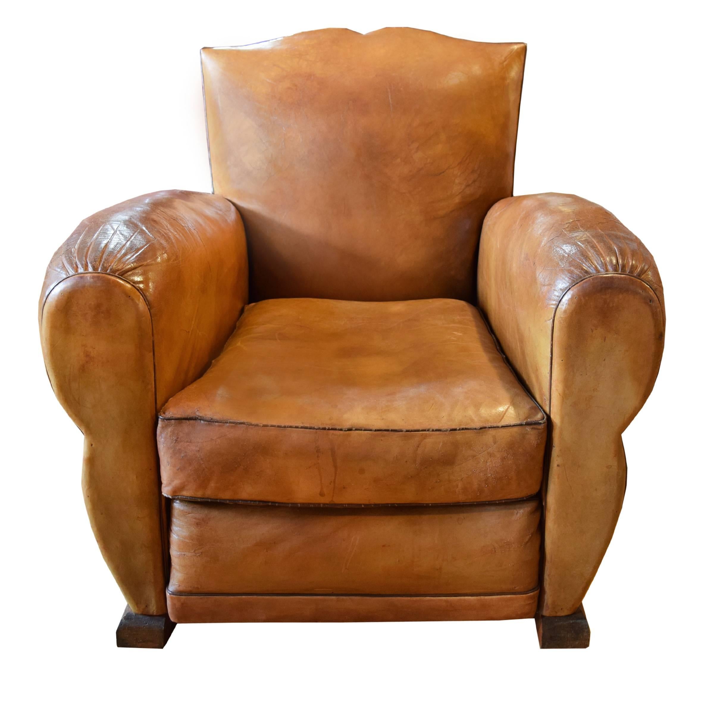 A pair of French leather club chairs with mustache form back, brass nailhead trim and wooden feet, circa 1930.
  