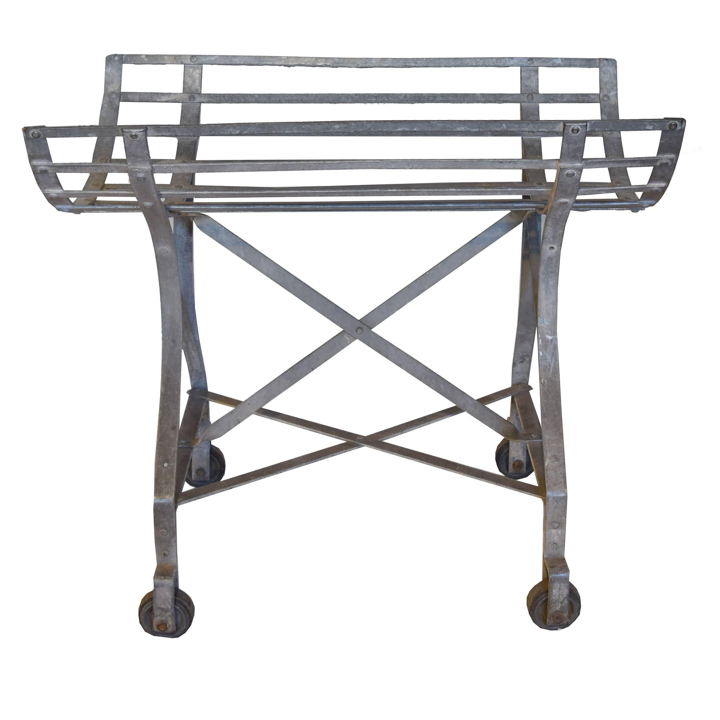 A French Industrial cart with a cradle-form top raised on four legs with wheels. Great for firewood or store display.
 