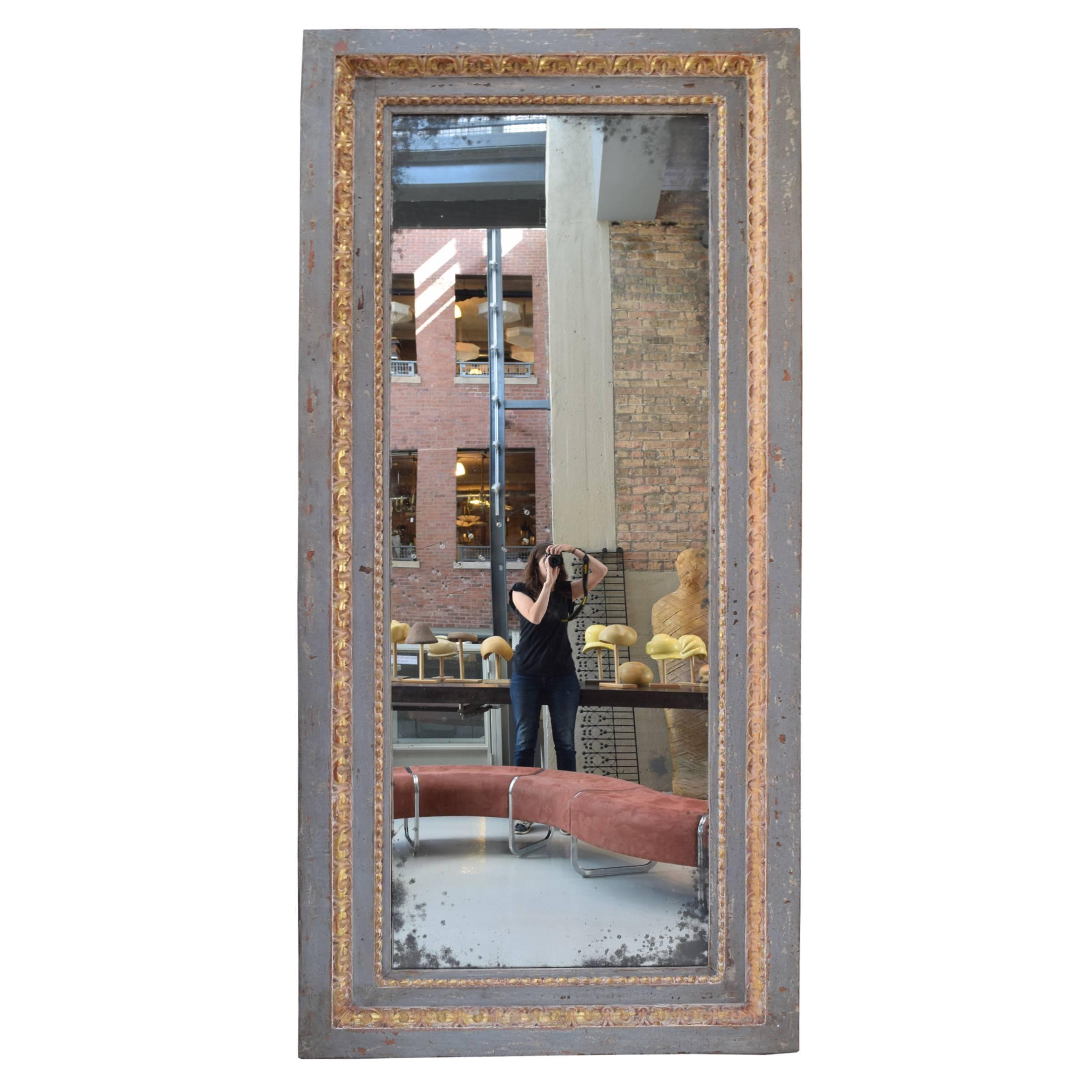 A monumental French mirror with antique glass and grey and gilt painted wood frame, early 20th century.
      