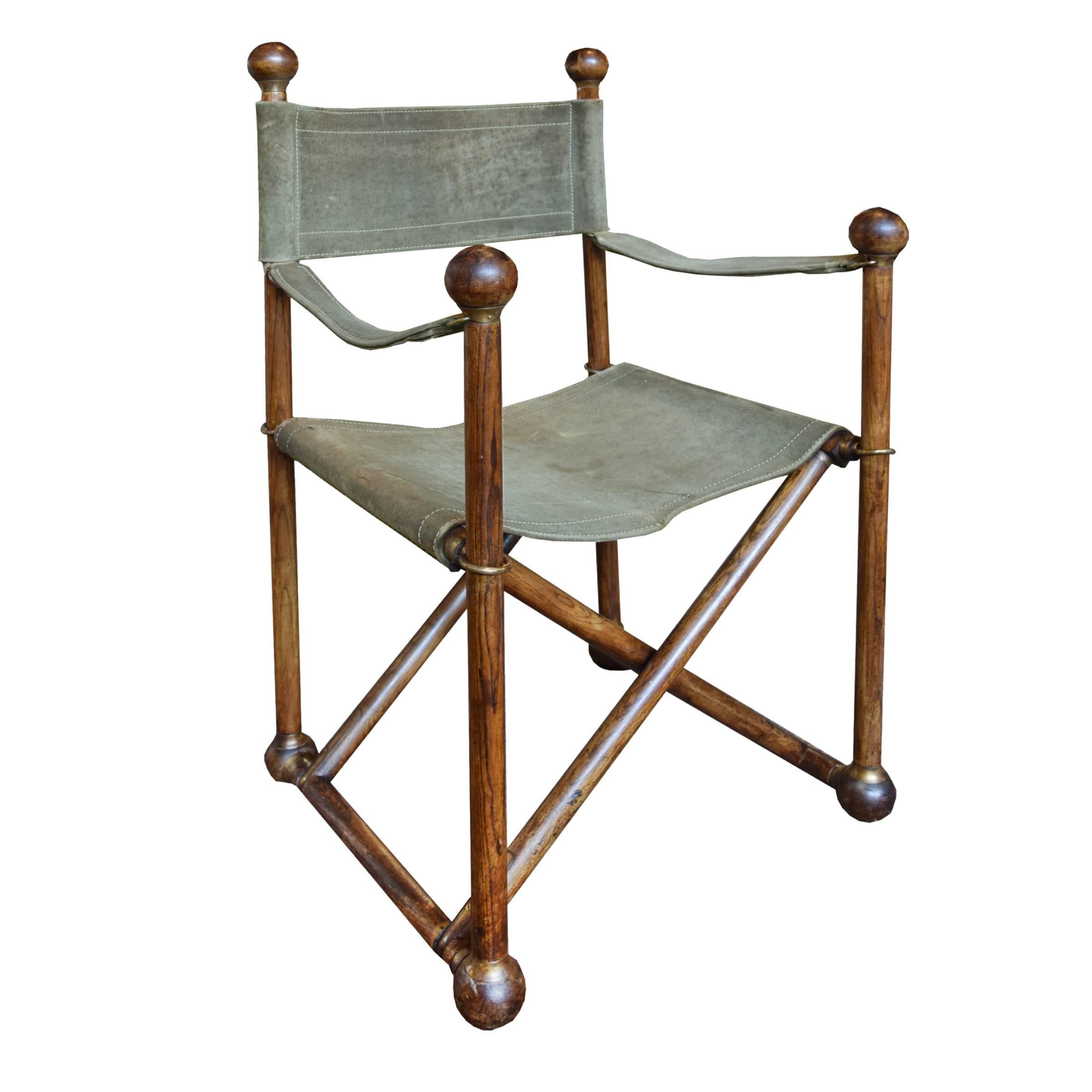 A French Campaign style wood frame folding chair with original suede seat, arms and back, having ball feet and finials and wonderful brass hardware.