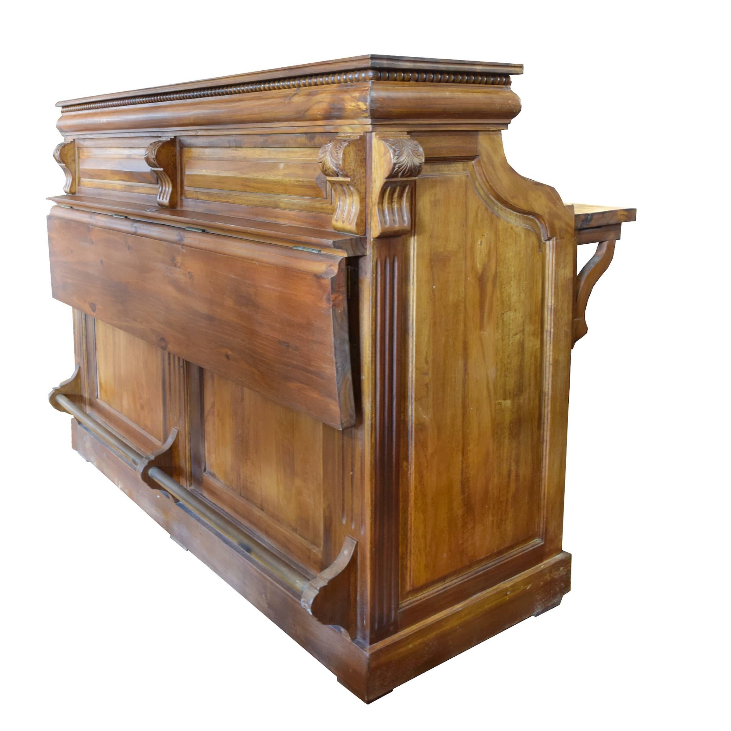 A French stand-up desk or bar with leaf extensions in the front and back, brass foot rest in the front, and moulded cornice with bead carving atop scrolling supports with acanthus leaf details. The back features two doors that open to reveal a large