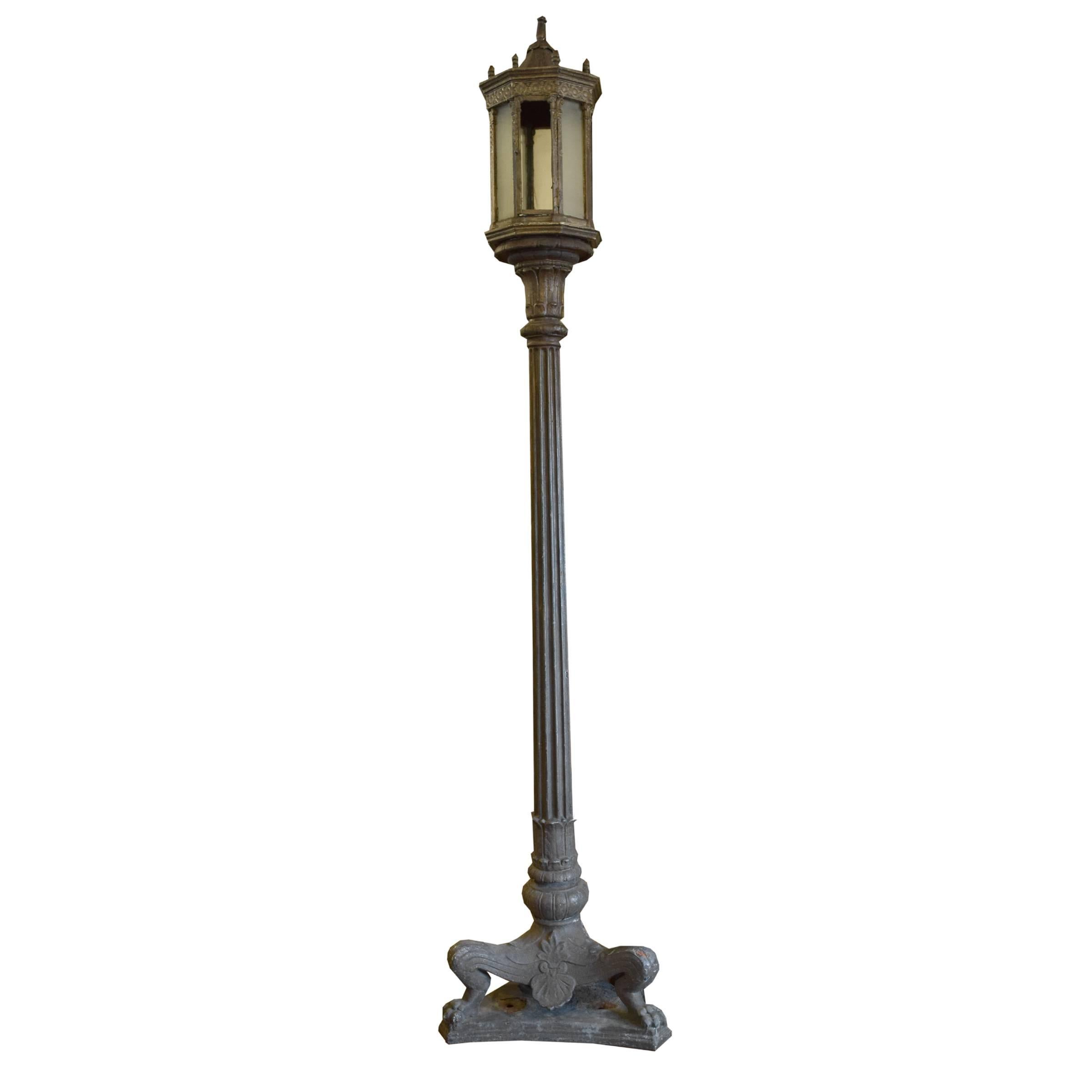A pair of American cast iron torchiere lights with octagonal shades, each having one hinged panel for access to interior, mounted atop a central fluted pole and ending in three lion legs with paw feet, raised on a curved triangular base.
 