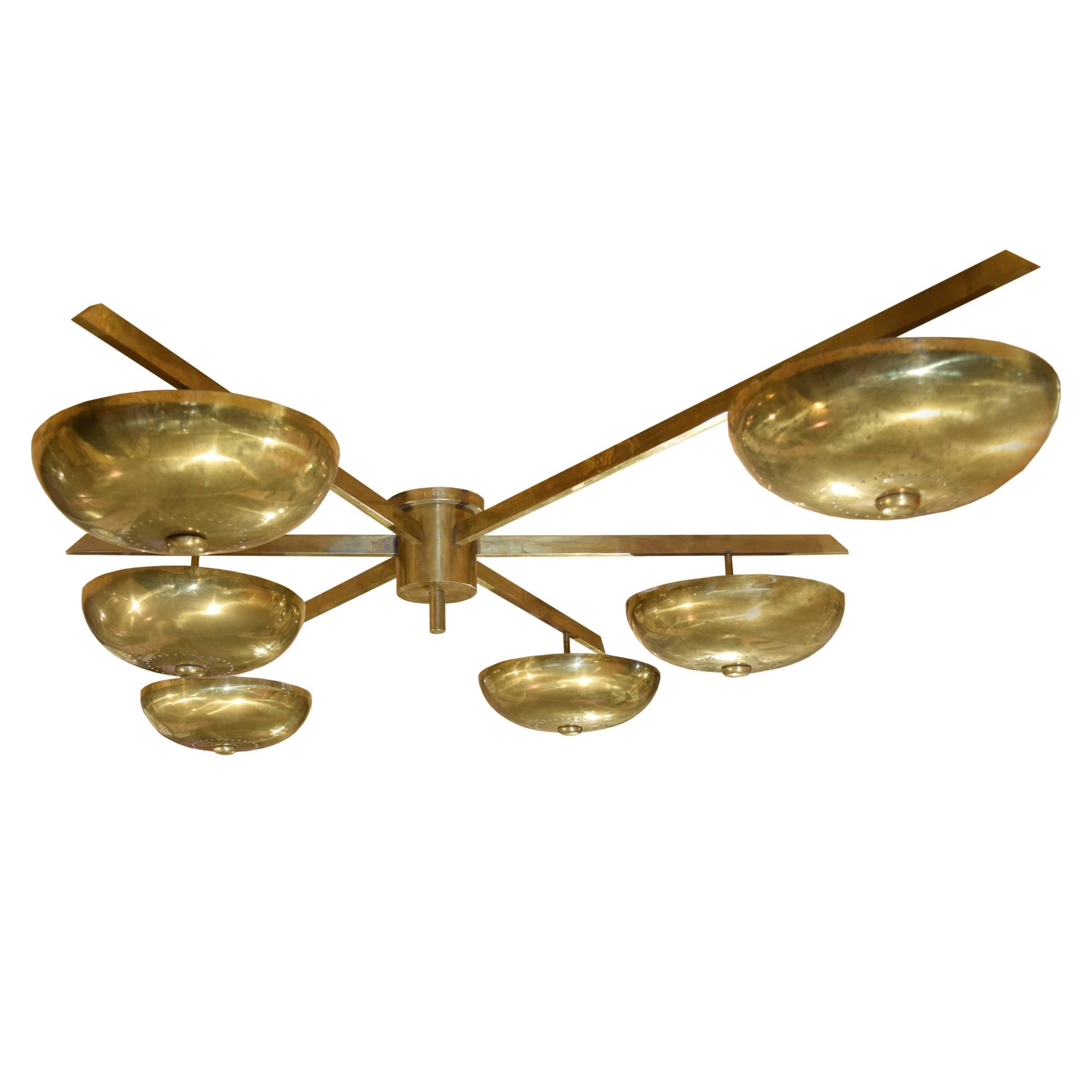 An Italian Arredoluce style brass flush mount chandelier, designed by Angelo Lelii, with an asymmetrical design consisting of six arms with dome shades. 
Requires re-wiring.