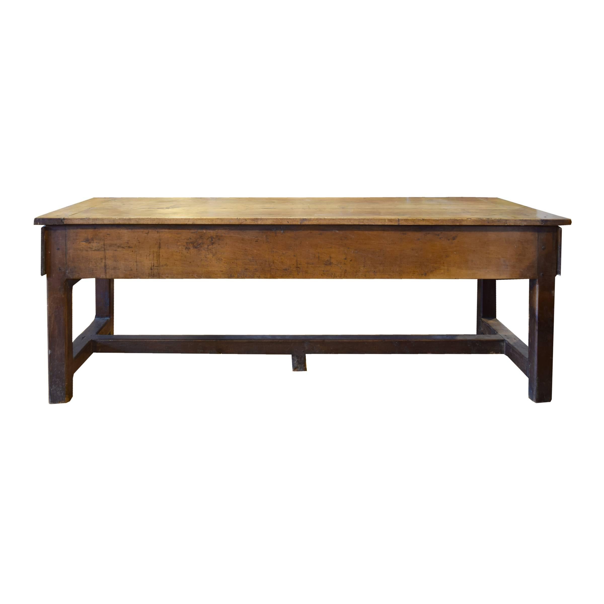 A wonderful French wood baker's table with four legs with stretchers and a central trestle. This table features ample storage with one door in the front and two large deep drawers on each side all having brass hardware.