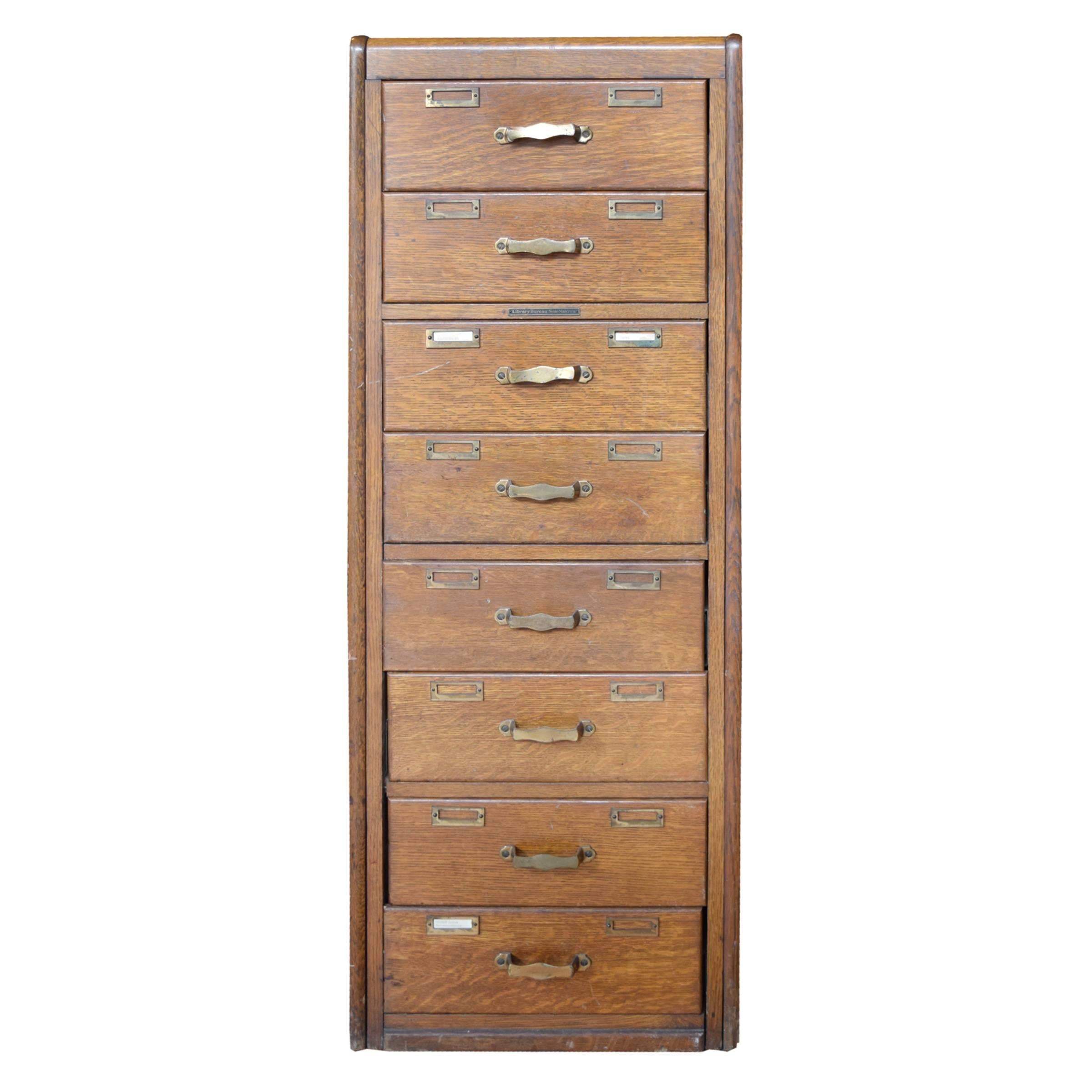 An American eight-drawer oak filing cabinet manufactured by Library Bureau with paneled sides and back, rounded top corners and original brass handles and card slots, circa 1910.