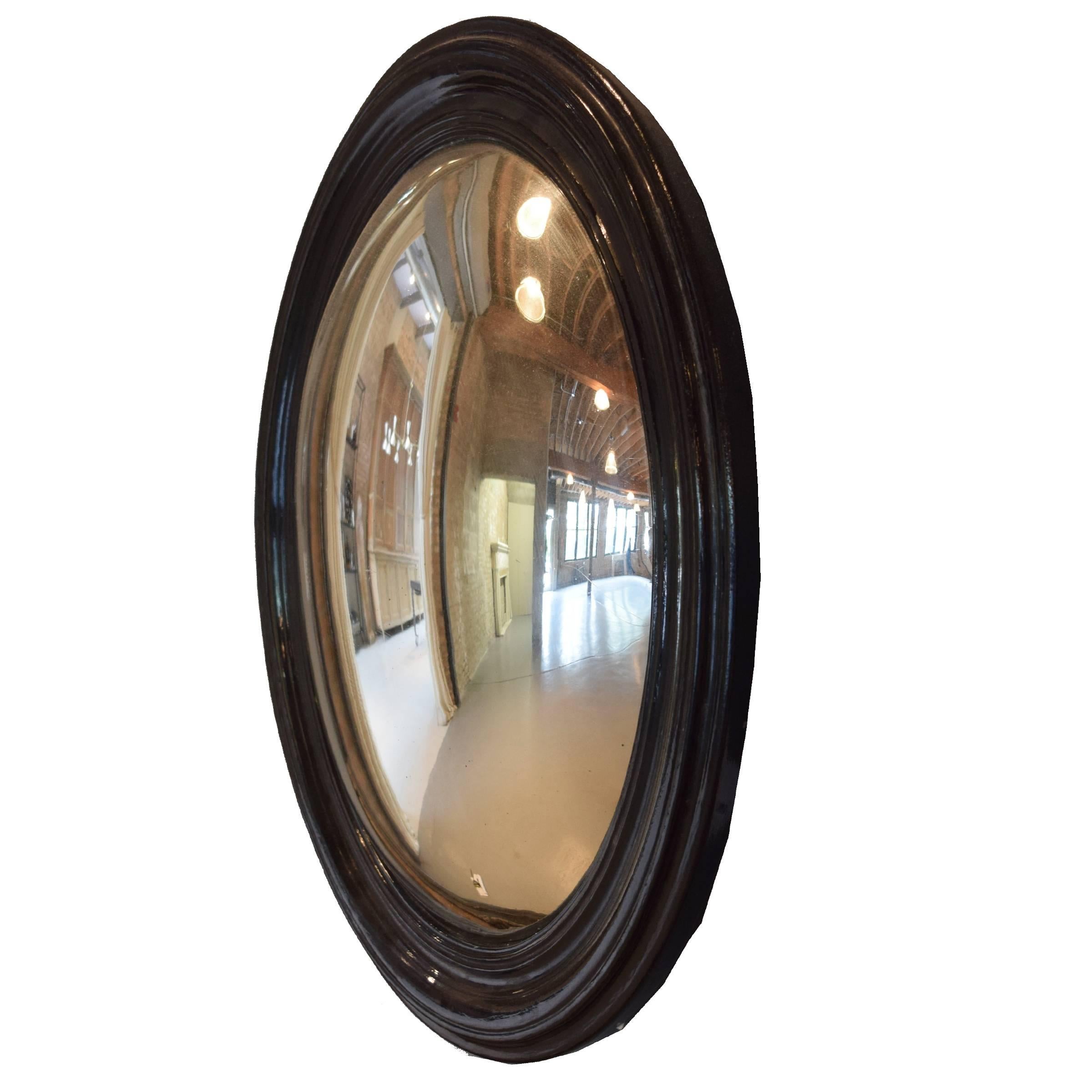A fantastic French oval convex mirror with an ebonized frame, 19th century.