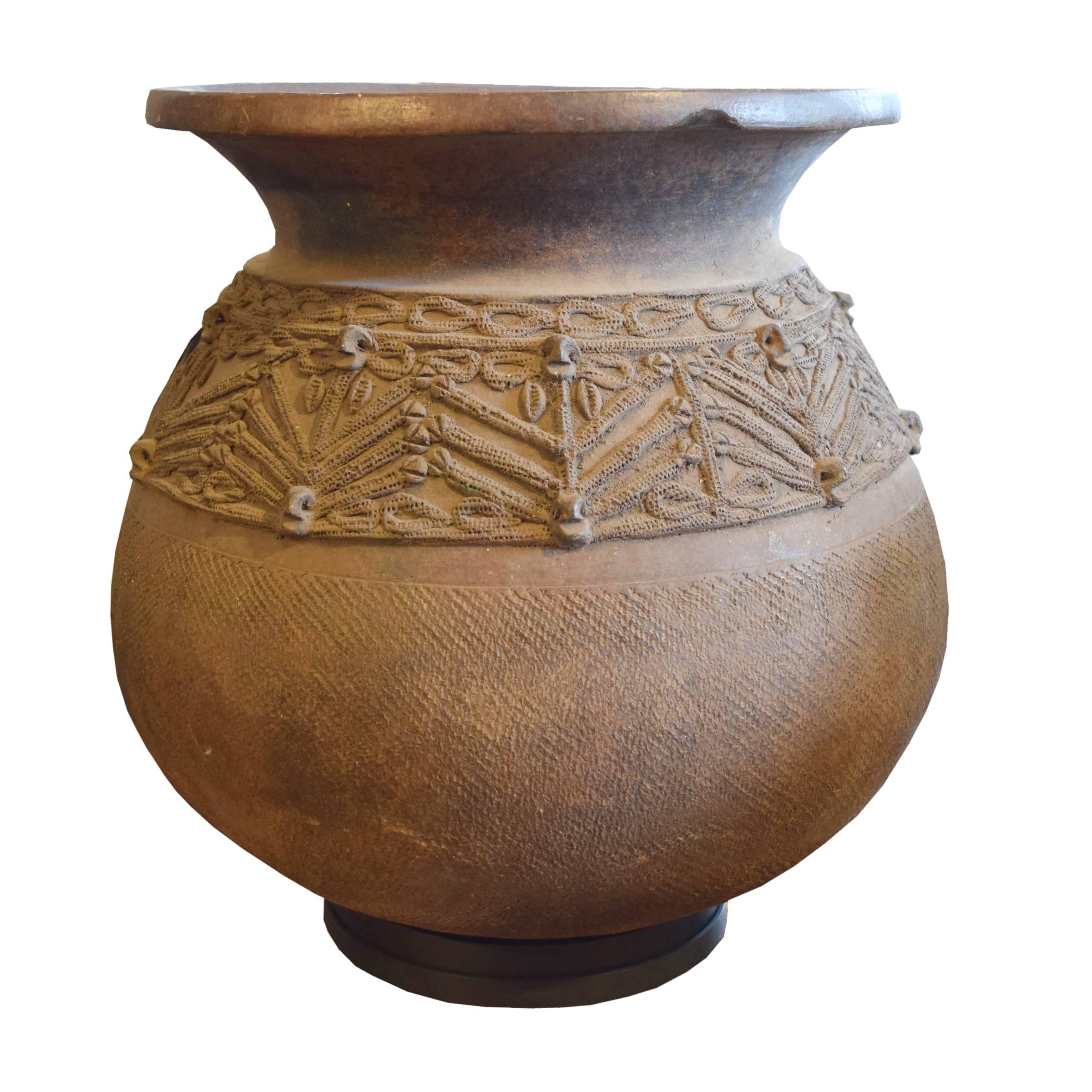 A hand-built African earthenware water vessel with applied relief. On a custom mount.