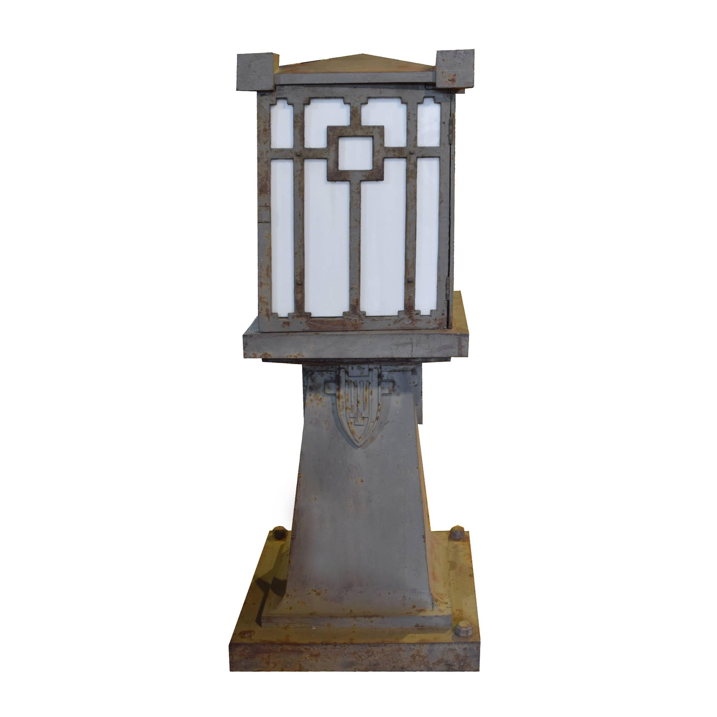 A pair of cast iron Prairie School bridge lights on fluted bases with a four sided shades with opaque glass, circa 1900.