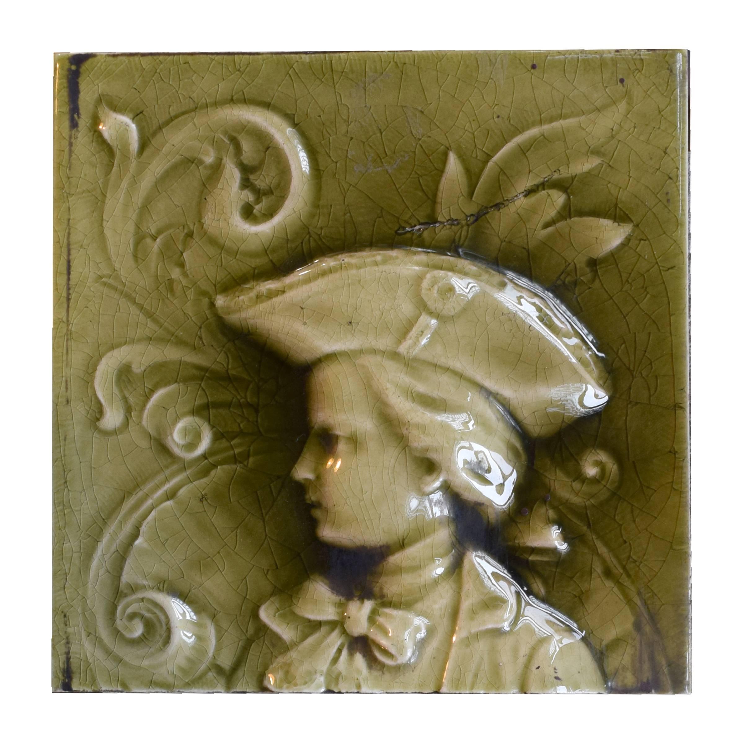 A fabulous three-piece glazed tile set in low relief by the American Encaustic Tiling of Zanesville, OH. depicting a man in 18th century costume. Stamped “A.E. Tile Co. Limited”, late 19th century. The American Encaustic Tiling (1875-1935) was, at