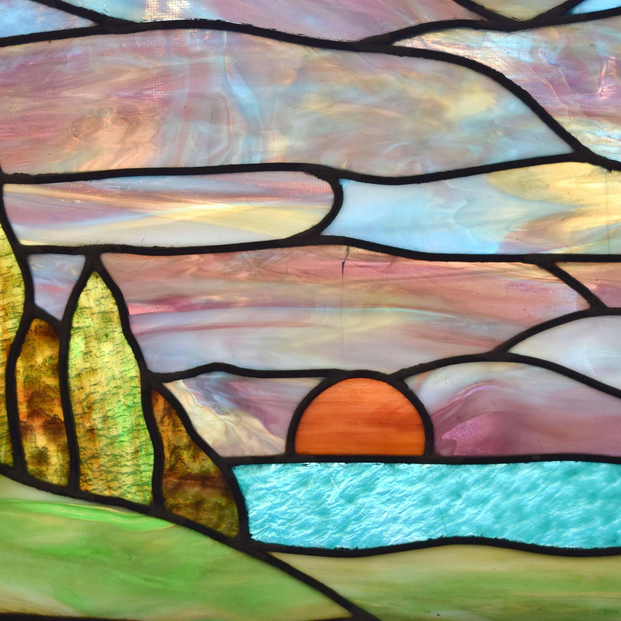An American stained glass window depicting a sunset over a landscape.