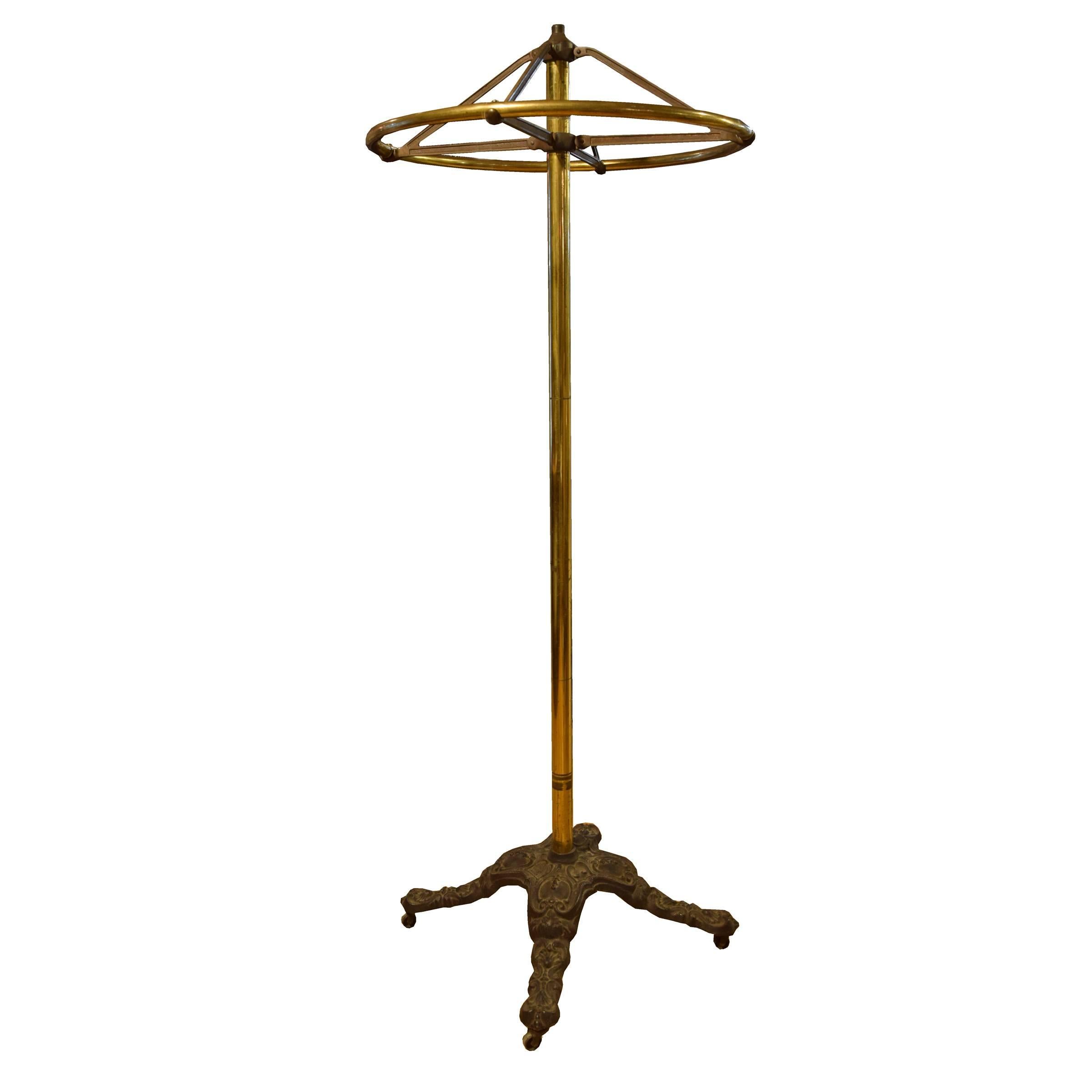 An American iron and brass circular rotating clothing rack with four cast iron legs on casters by Great Western Fixtures, Chicago, IL, late 19th century.