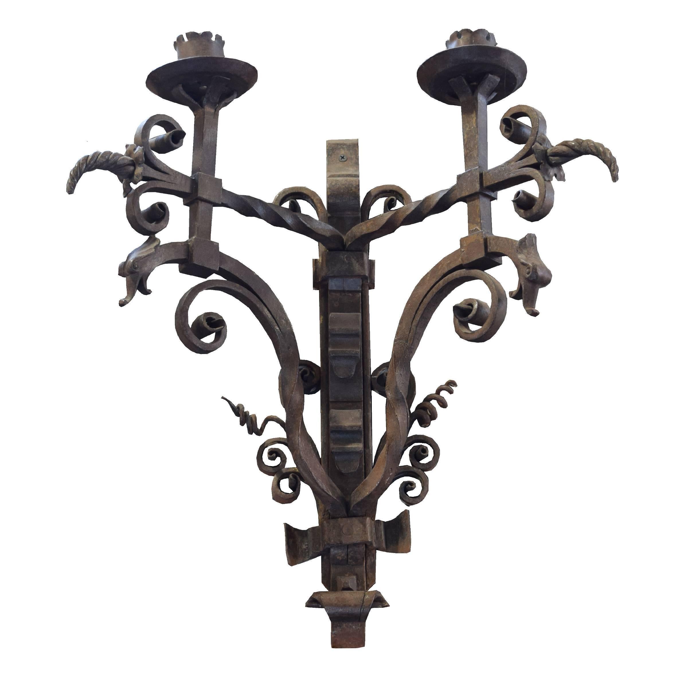 A fantastic pair of French expertly wrought iron two-candle sconces with griffins and an elaborate scrolling motif, 19th century.