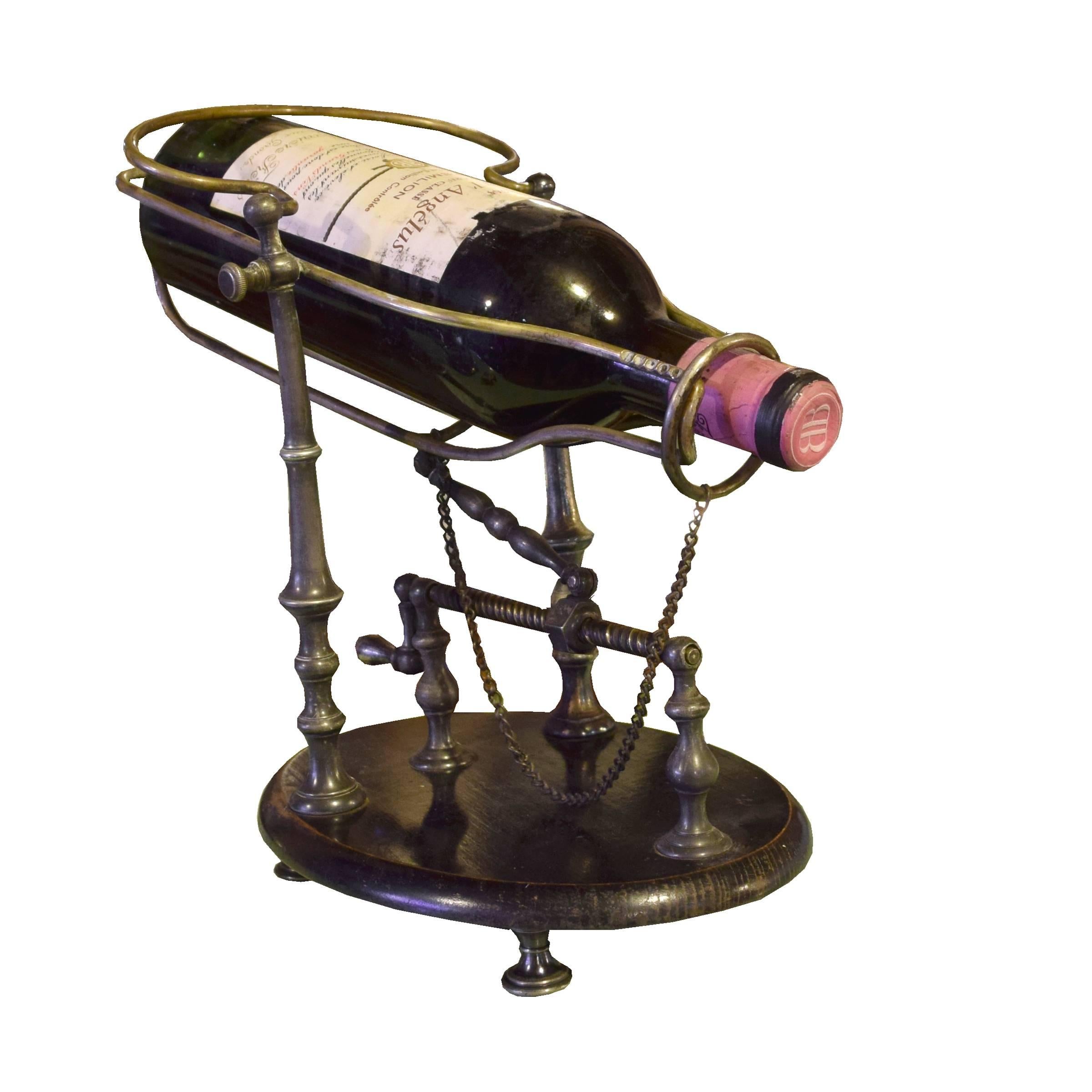 A fantastic French wine decanting cradle with a brass bottle cradle and wood base with brass feet. Turning the handle activates the cradle, bringing it forward and tilting it to achieve the perfect angle for pouring while keeping any sediment in the