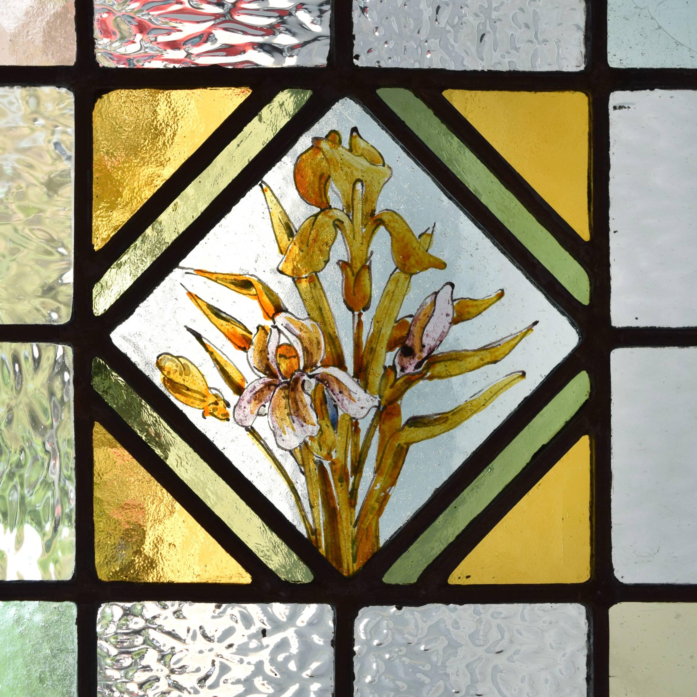 A lovely English art glass window with a central medallion of birds on a branch, flanked by irises and daffodils, circa 1880.
