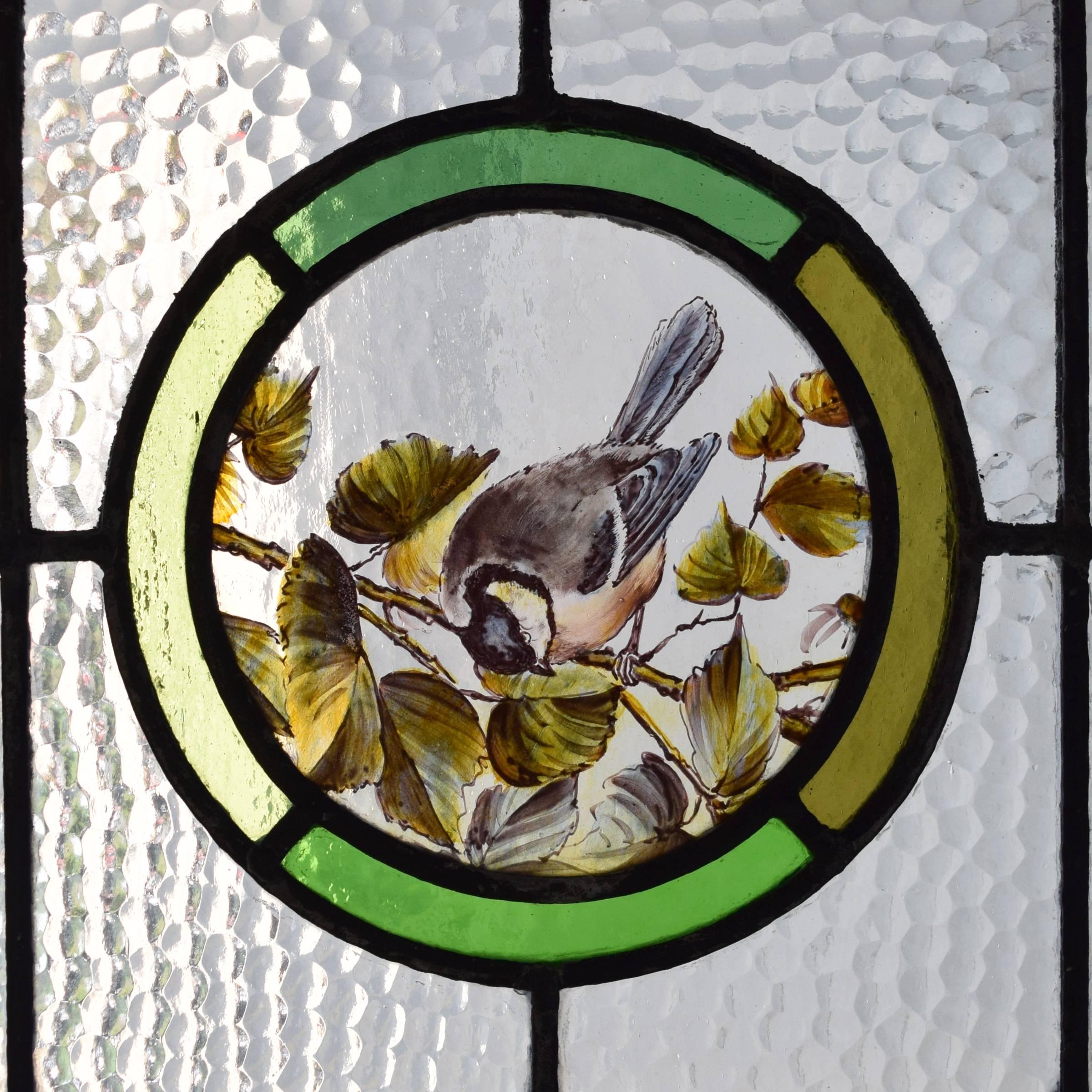 A fantastic English art glass window with red and green borders and a central medallion with a hand-painted robin resting on a branch, circa 1880.