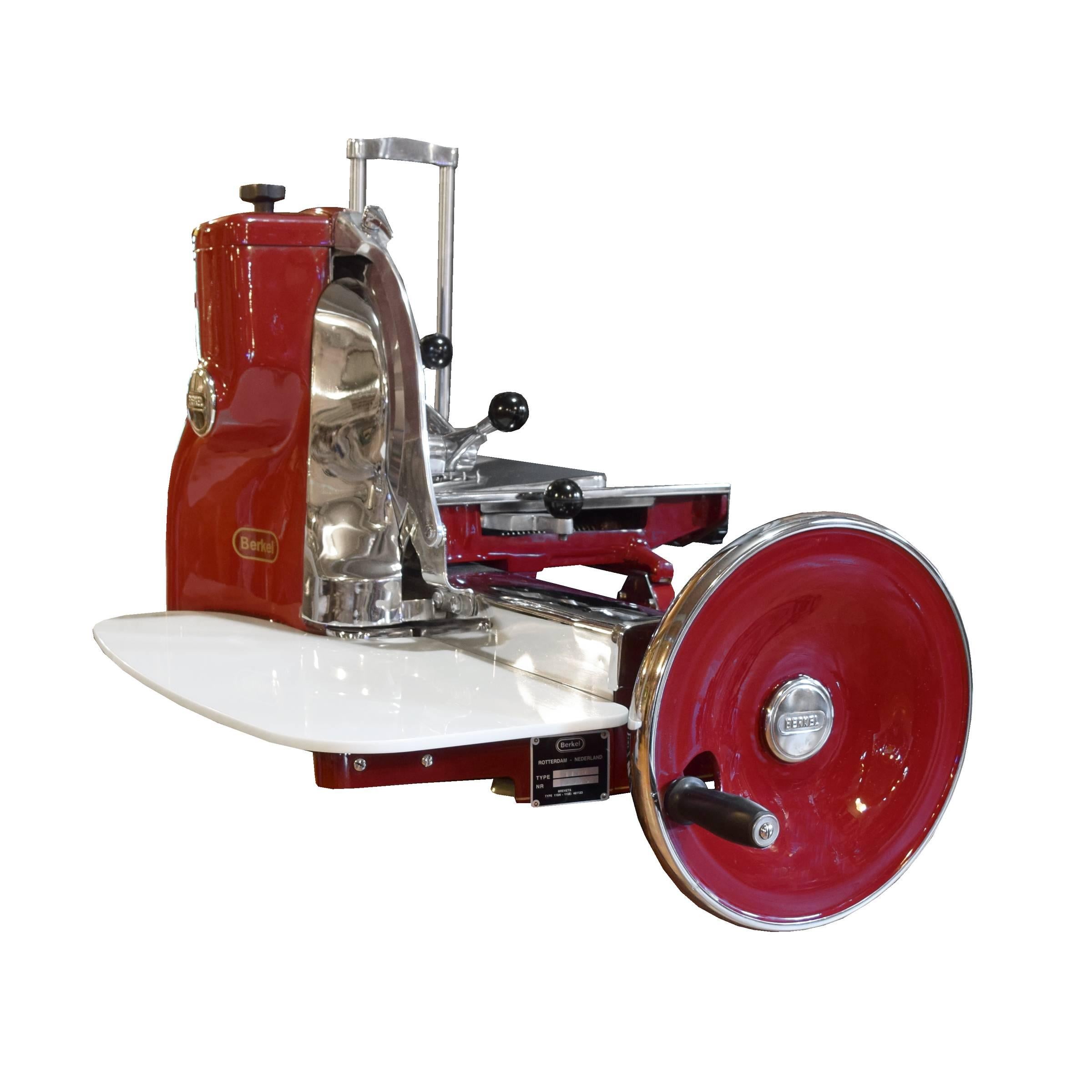 A rare Berkel model 115H meat slicer in red high gloss enamel, manufactured in Rotterdam, Holland. This model, manufactured from 1953-1980, is flywheel operated and features 15 different slicing thicknesses and a blade sharpener. This slicer has