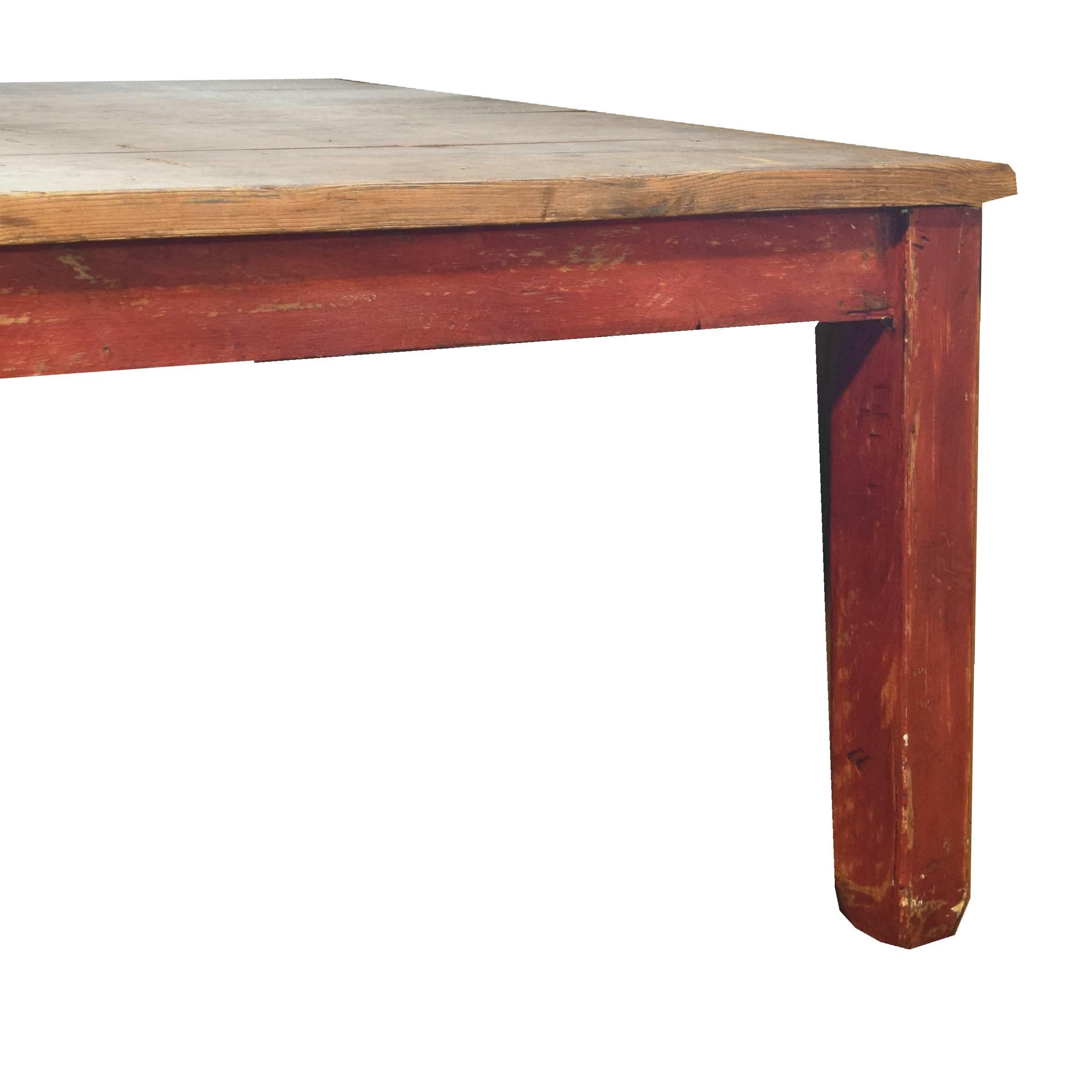 A monumental Italian work table with an incredible unfinished wide plank pine top and red painted square legs with tapered feet, circa 1900.