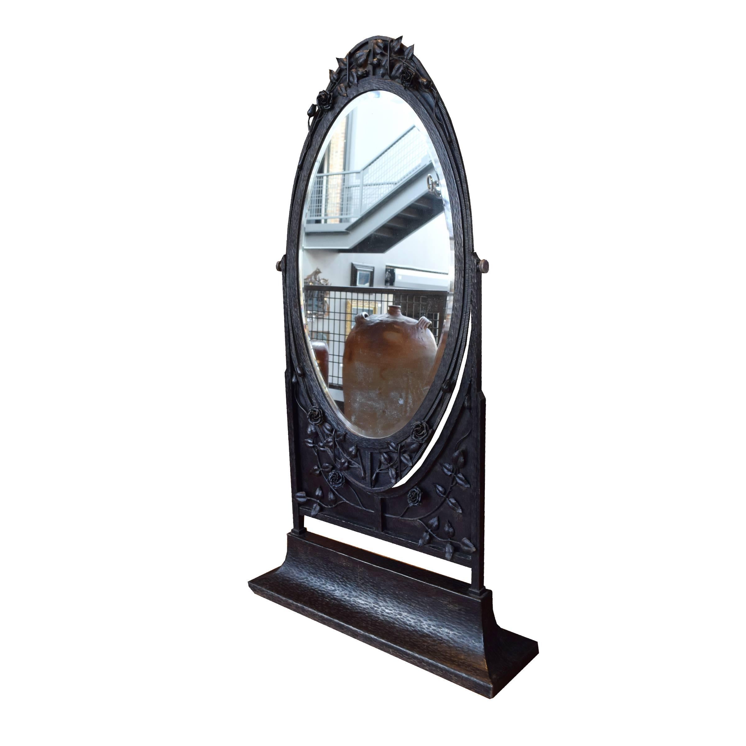 A gorgeous French fer forge pivoting dressing mirror on wheels with beveled oval glass and a lovely hand-wrought rose and vines decorated frame, circa 1920s.
