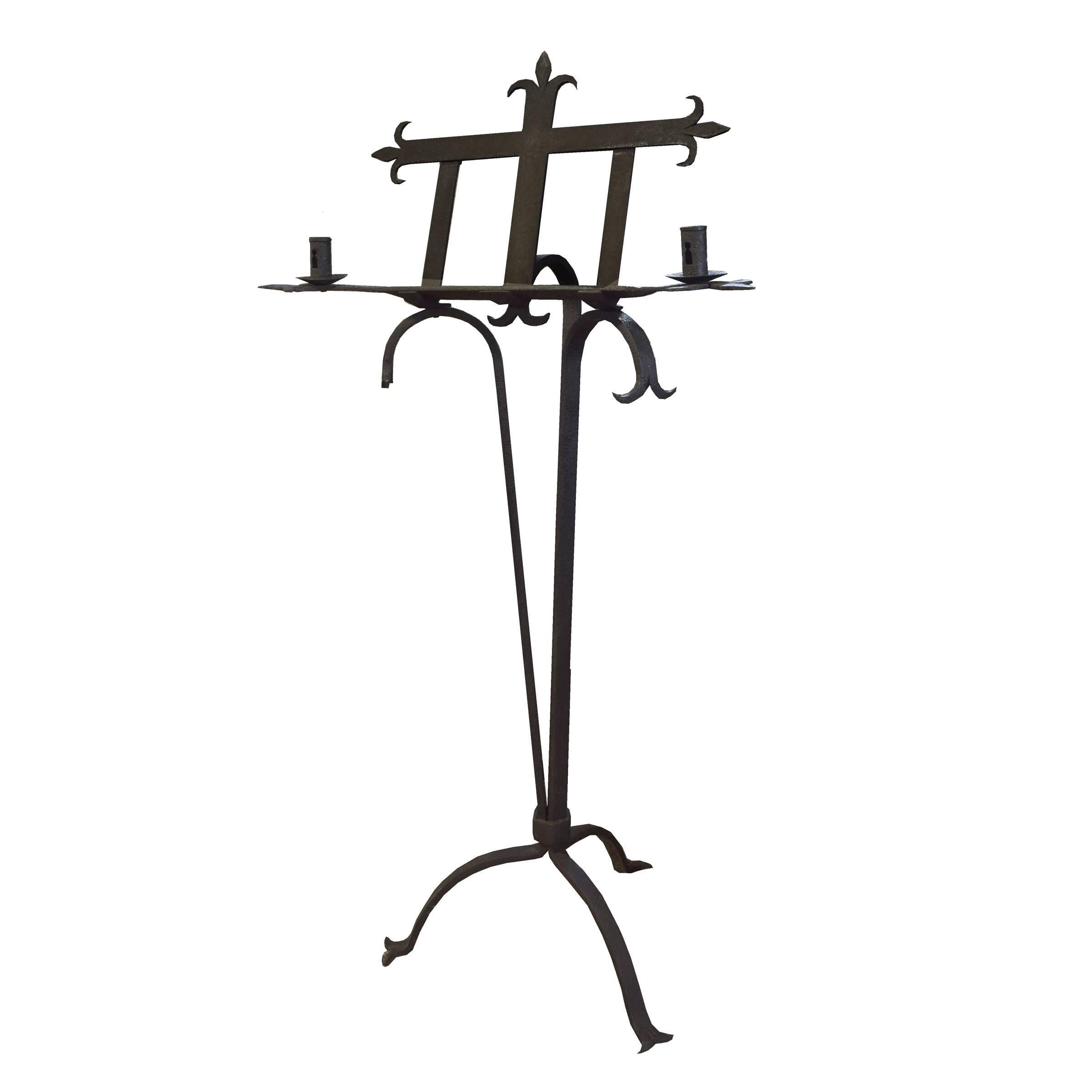 A fantastic French wrought iron book/ music stand with a fleur-de-lis motif, two candle holders, and three legs, circa 19th century.