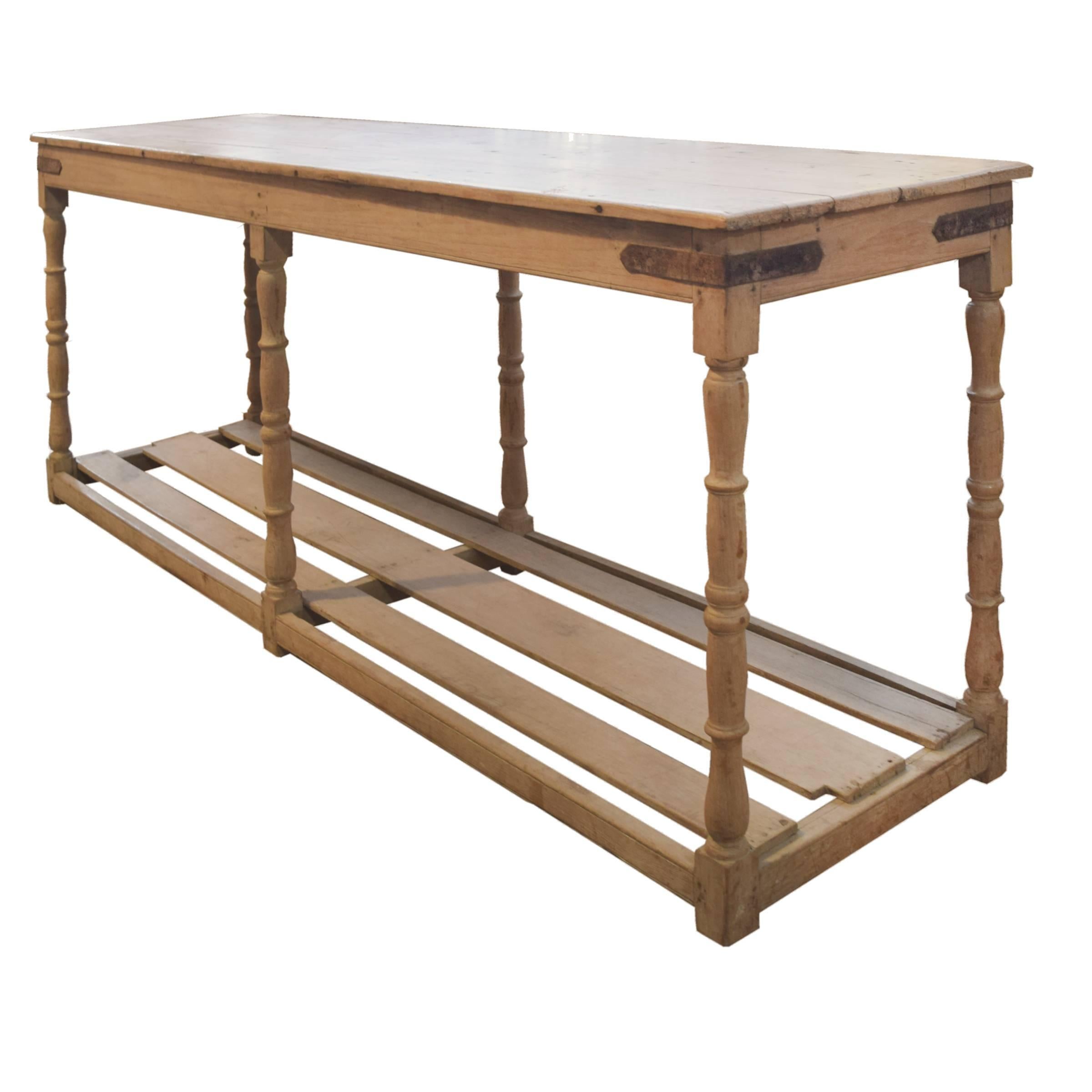 A great French wood draper's table with iron corner details, six turned legs, and a slatted shelf at the bottom, circa 1900.