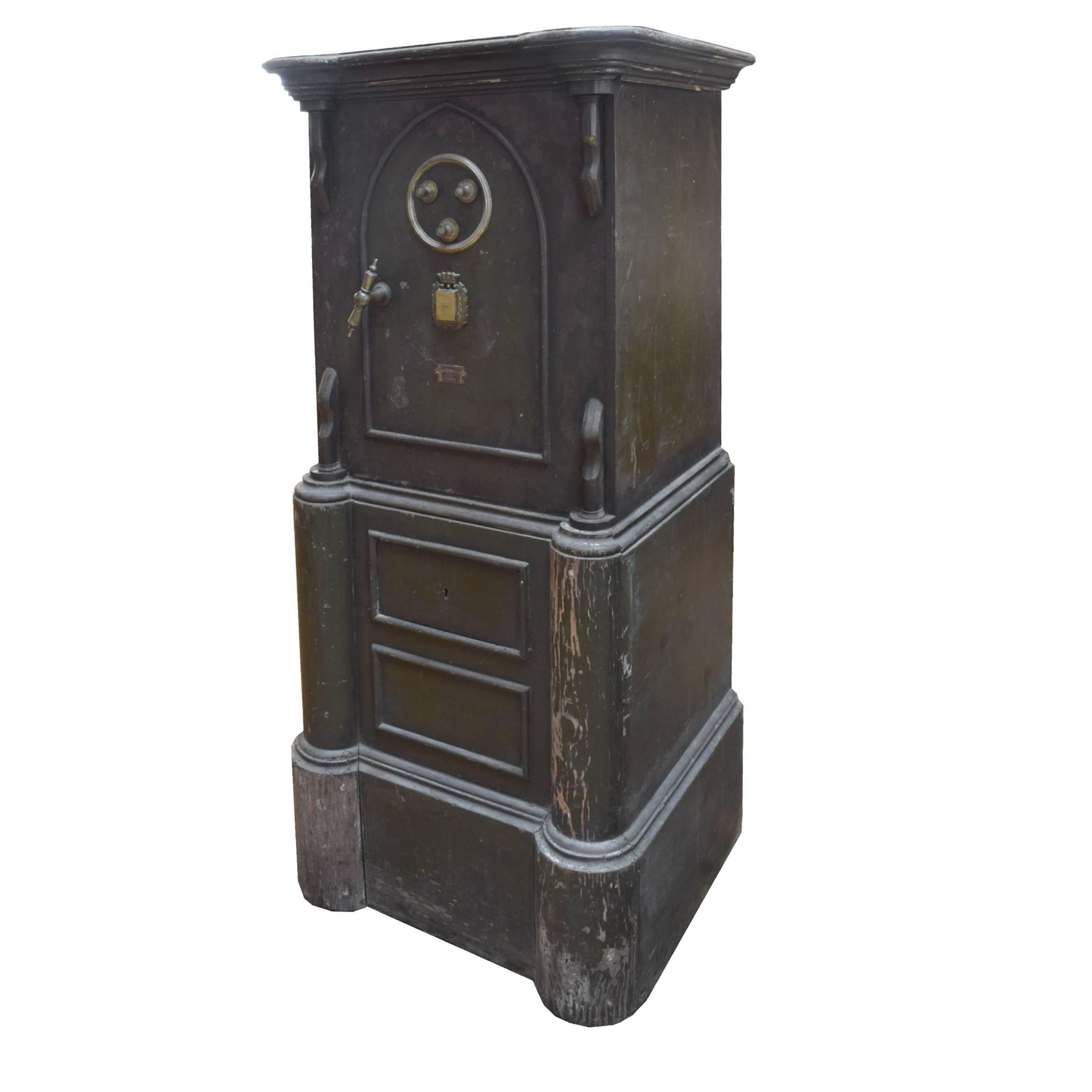 A very cool iron Spanish safe with a brass handle and three letter combination dials, with a wood top and a tall wood base, circa 1900.