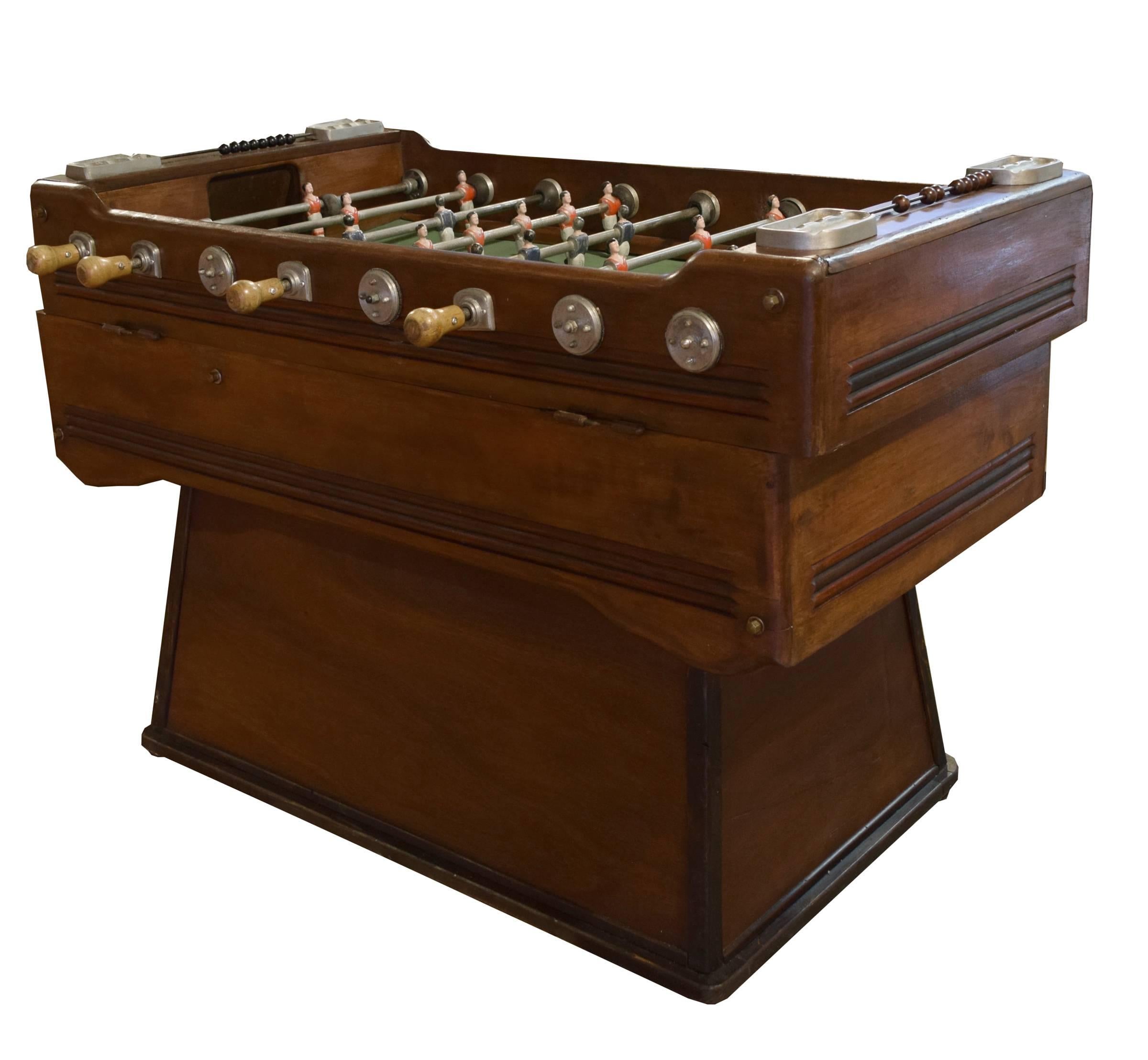 A stunning dark wood foosball table from Italy. This Mid-Century table is coin operated and features metal players painted in blue and red. There are manual scoring mechanisms on both ends, as well as four ashtrays.