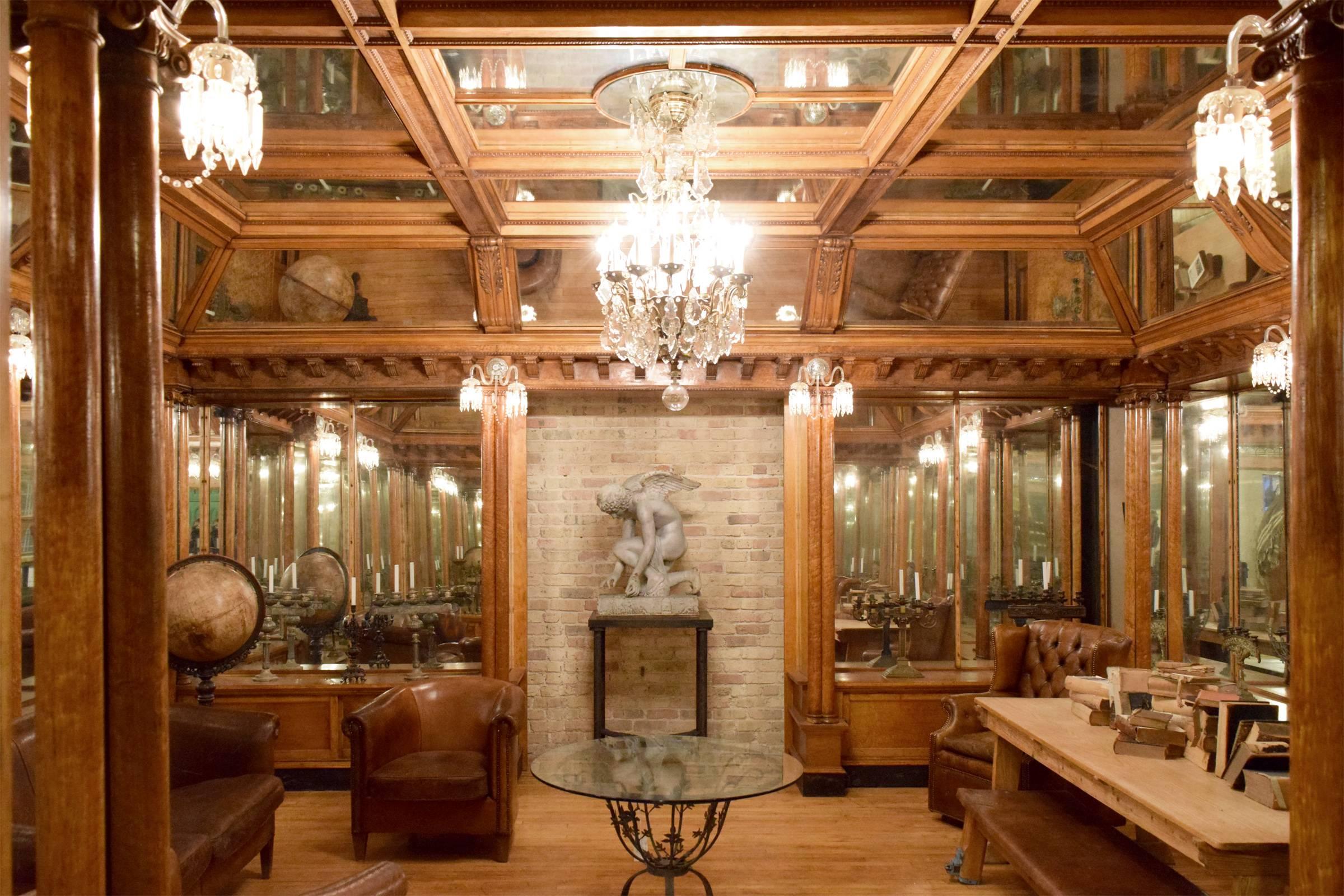 An incredible bird's-eye maple and mirror room from a Nashville, Tennessee jewelry store. This stunning room includes a crystal chandelier and eight crystal sconces. Double ionic columns stand below the corbel crown with egg and dart detailing that