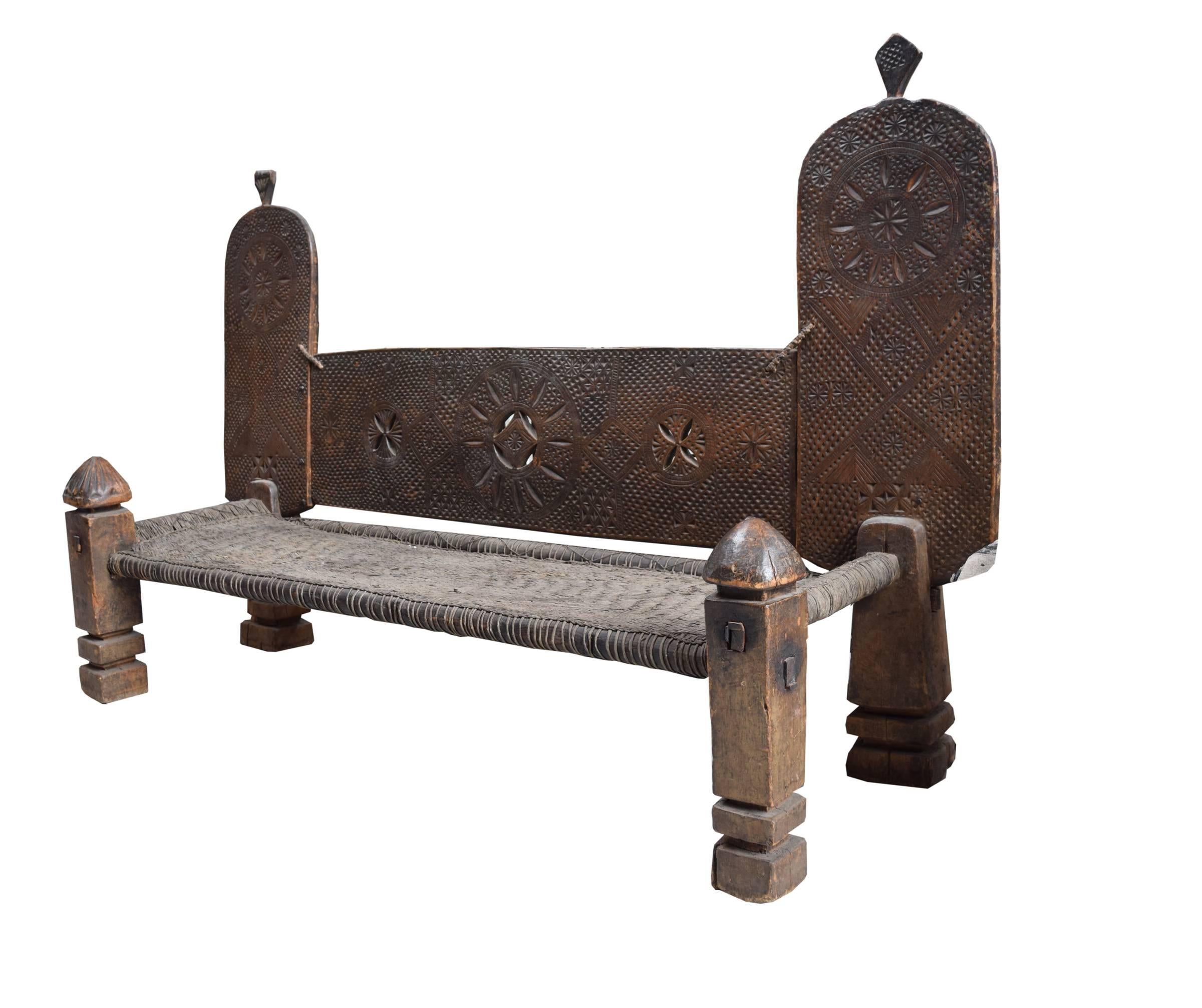 Monumental 19th century Swat Valley bench with chip carved back in geometric patterns, large front legs with carved finials, and a woven hide seat. The largest we have ever seen.
