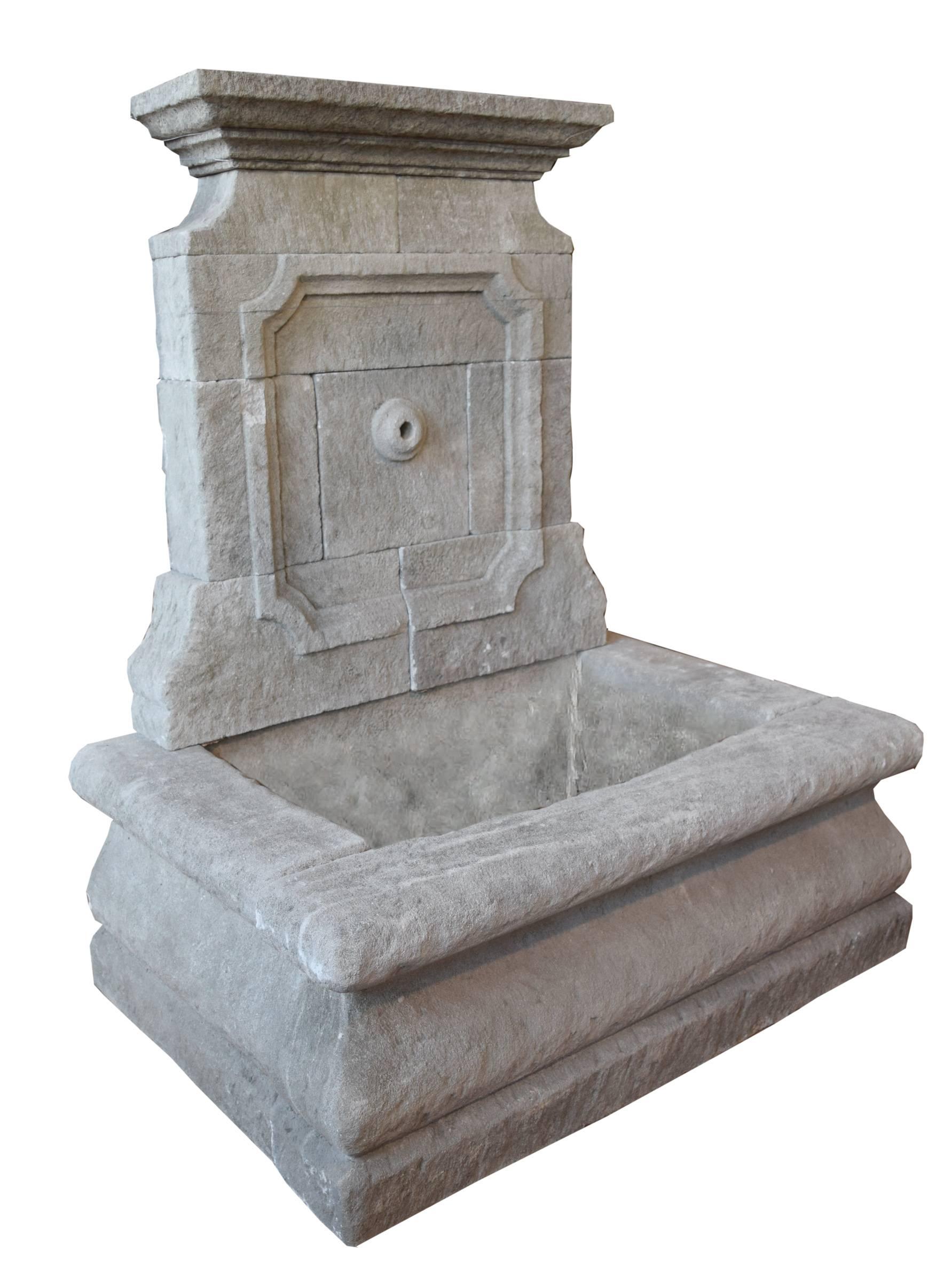 Provincial French carved limestone wall fountain with classical pediment, central spout, and rectangular basin, 19th century.