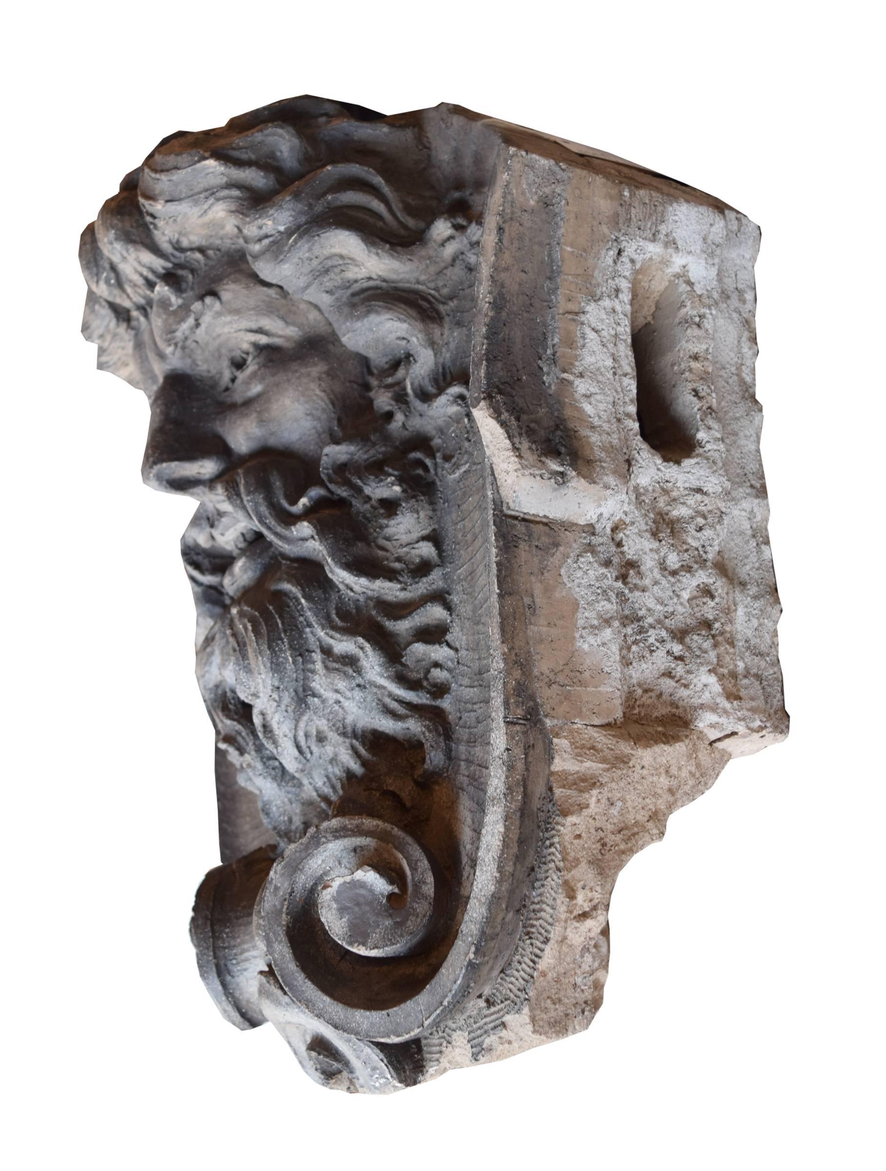 American terra cotta building ornament depicting a wise grinning man with flowing hair resting atop a scroll form, circa 1900.