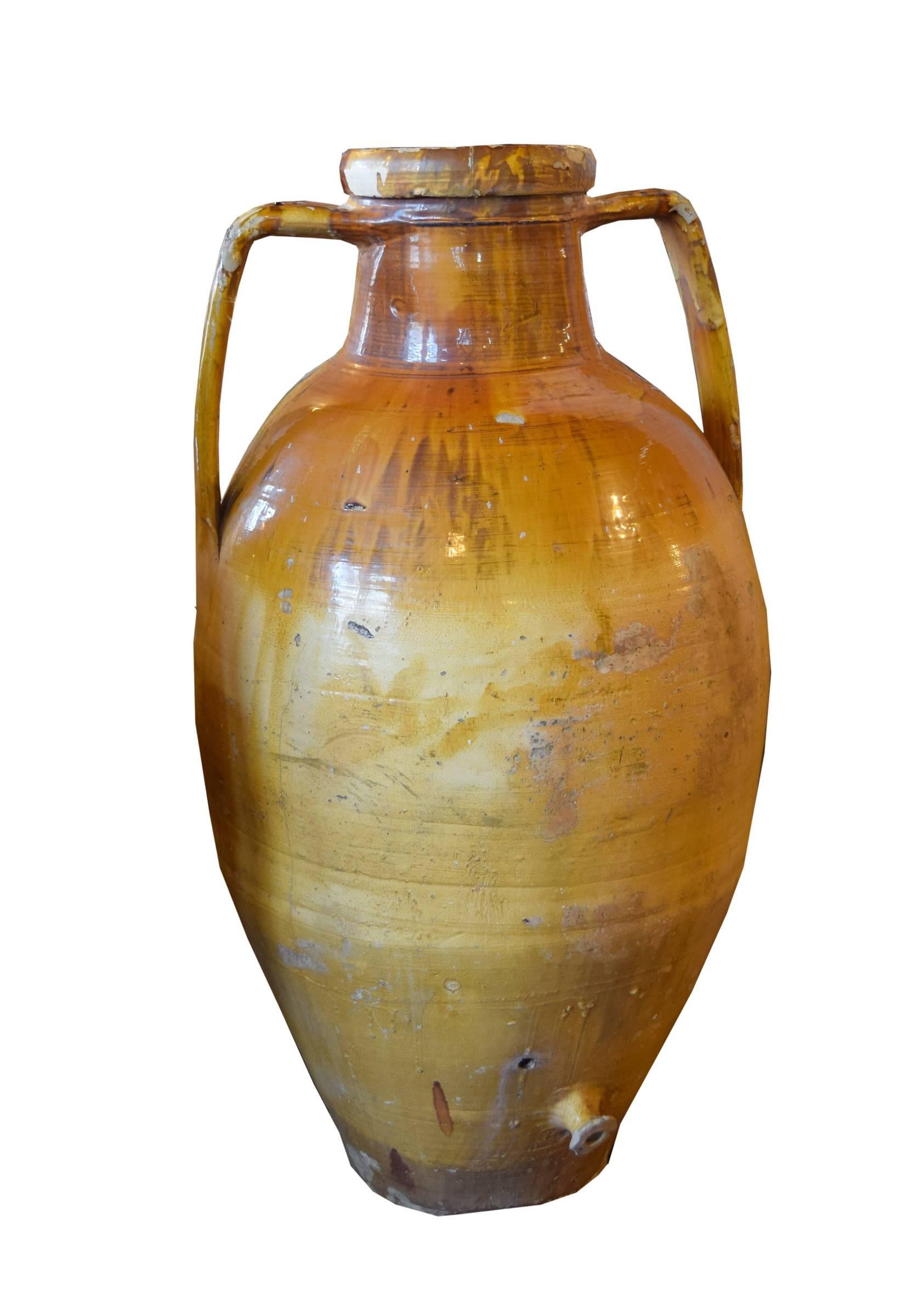 A 19th century Italian terracotta amphora form olive oil vessel with a beautiful glaze and a spout at the bottom.
