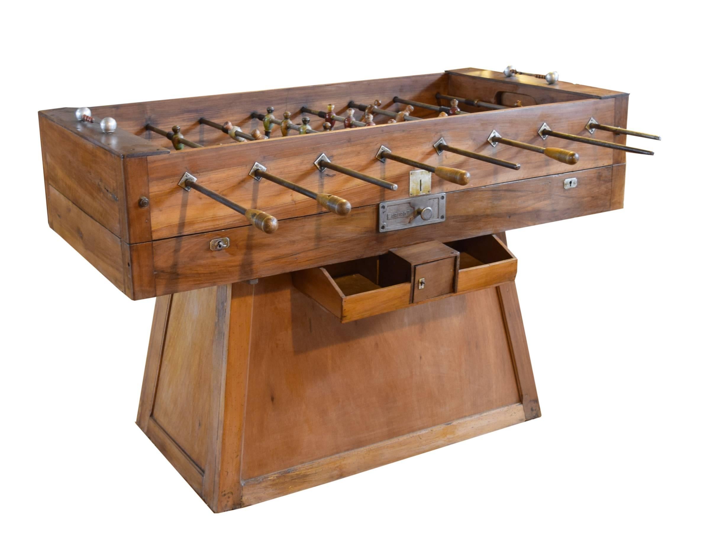 A coin operated wood foosball table from Italy. This circa 1930s table is an early example of a foosball table given that they were first invented in 1922. The original wooden players are painted red, green and white.