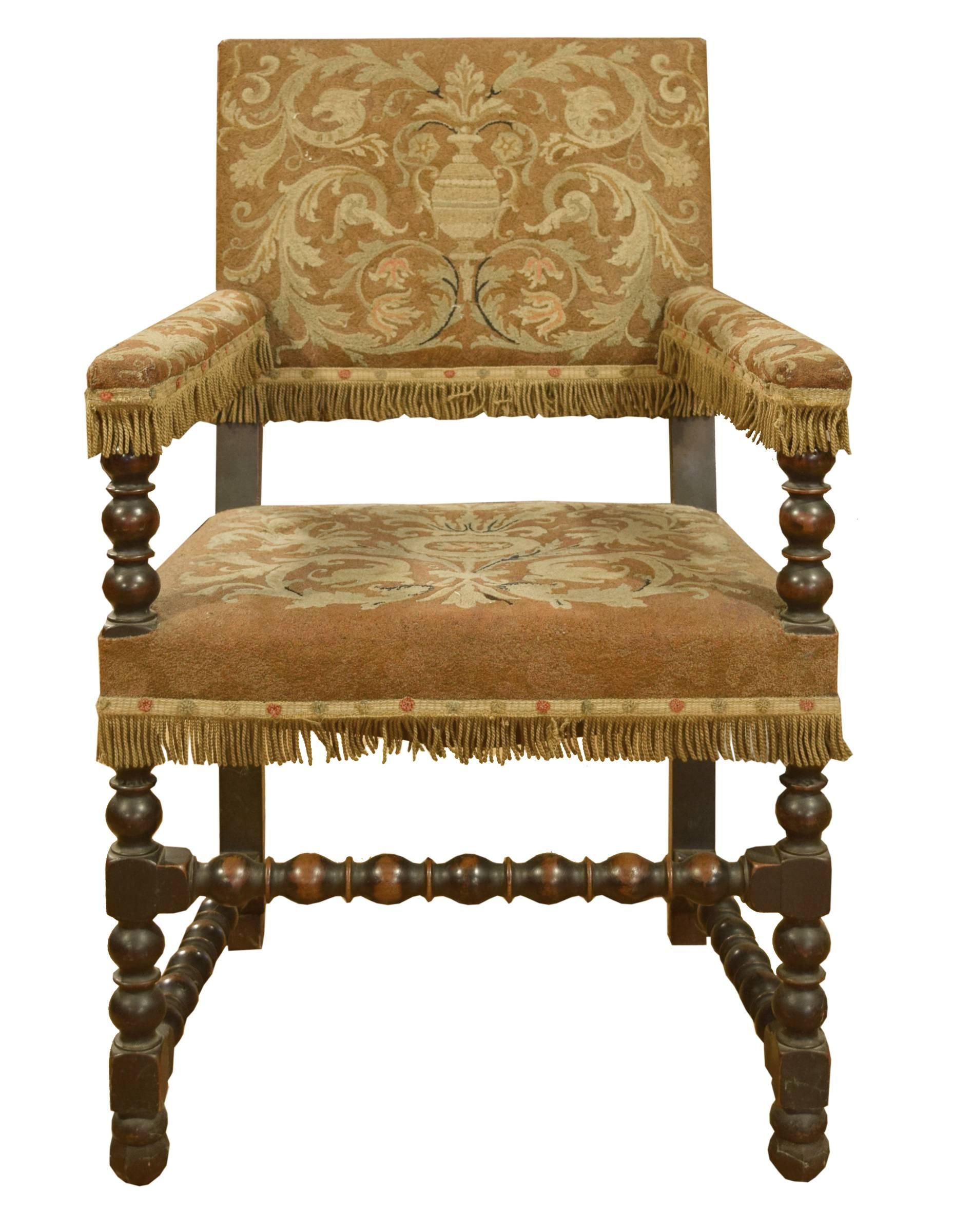 Set of twelve English Tudor style dining chairs, consisting of two armchairs and ten side chairs with turned legs and stretchers and embroidered upholstery with fringe trim. circa 1920.

Side chairs: 21" x 18" x 41"