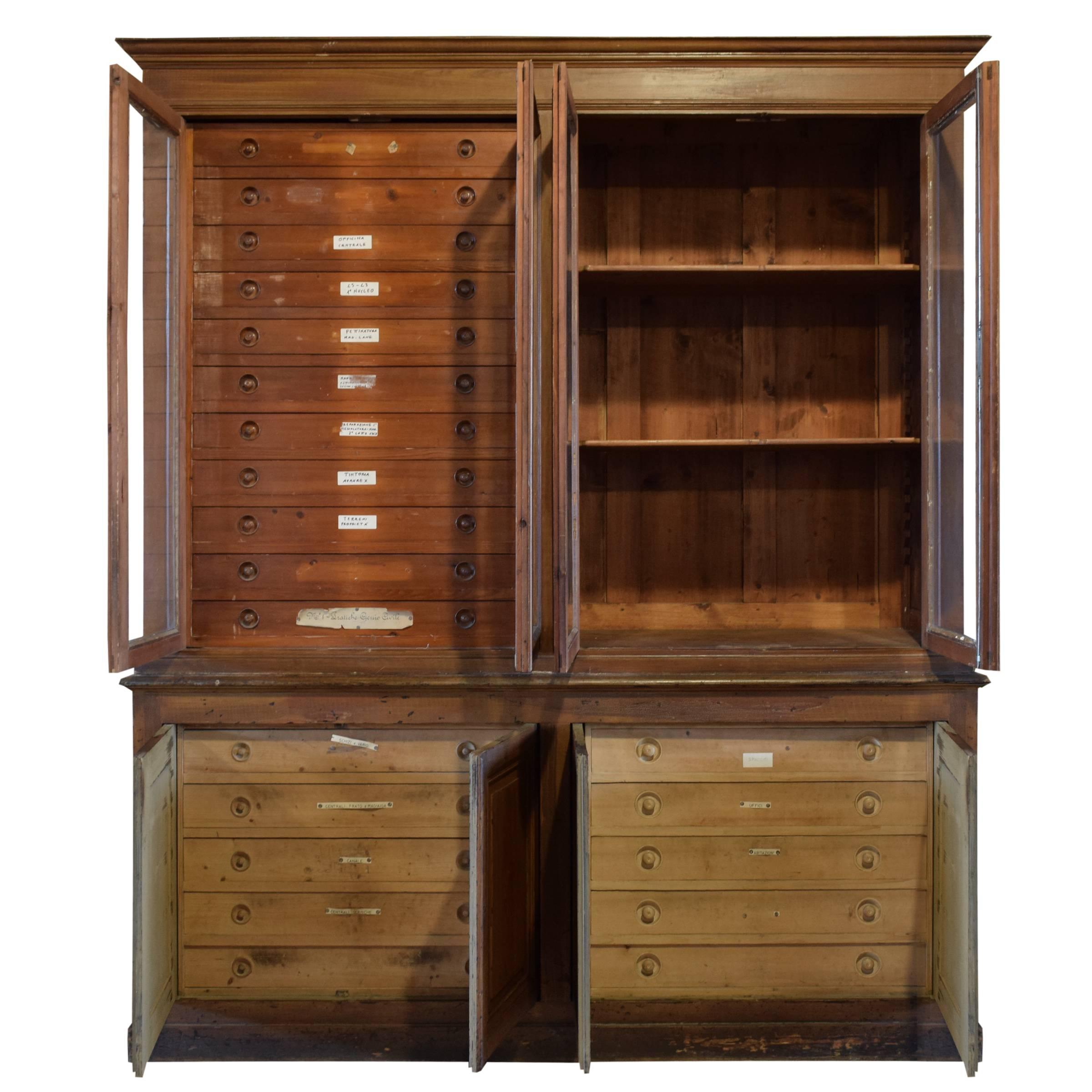 Large Italian wood specimen cabinet with original glass doors with eleven drawers and three shelves on the top and four wood doors and ten drawers on the bottom.