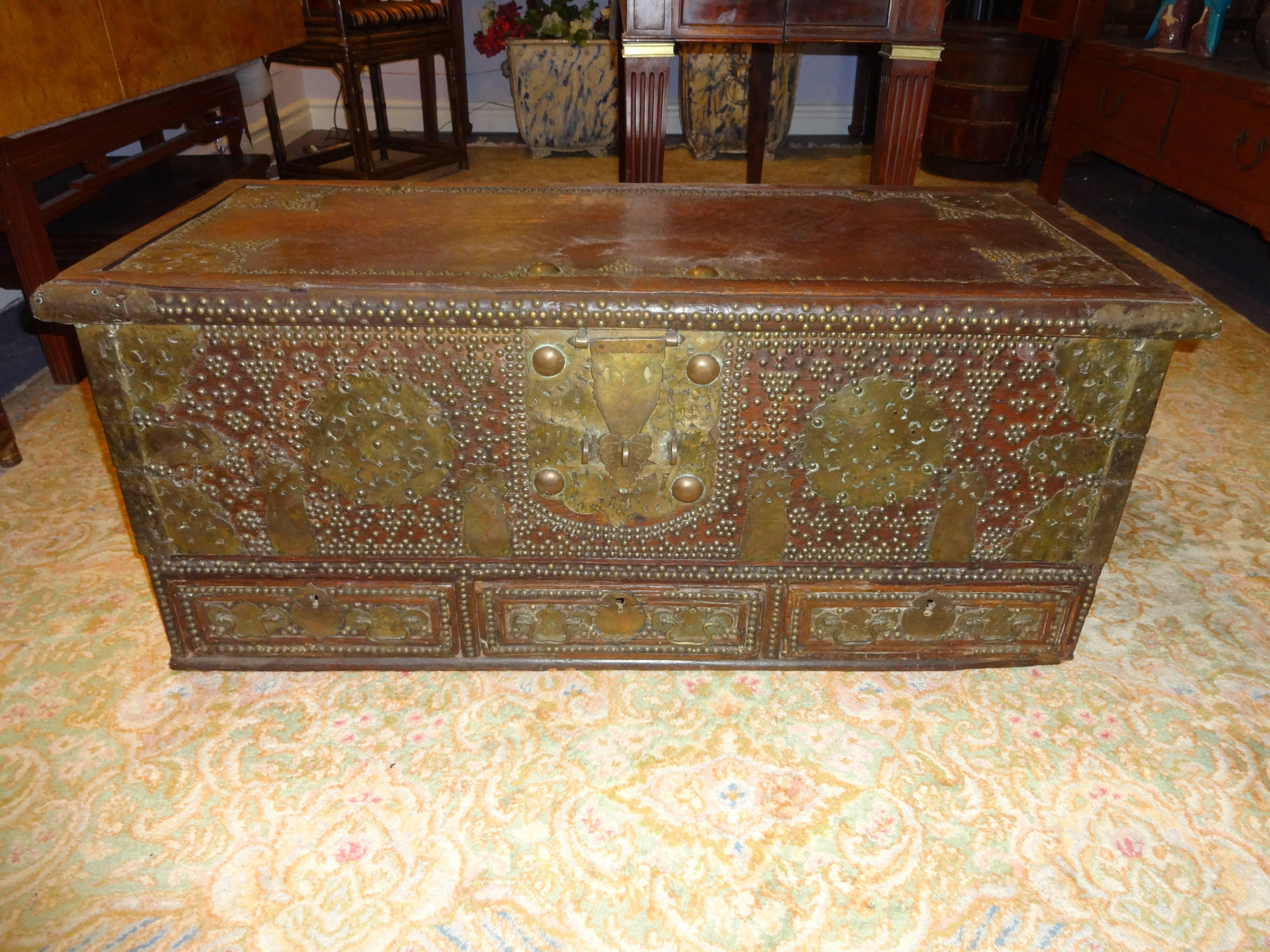 A wonderful Kuwaiti wooden top opening storage chest adorned with brass hinges, handles and embellishments with three drawers at the bottom.