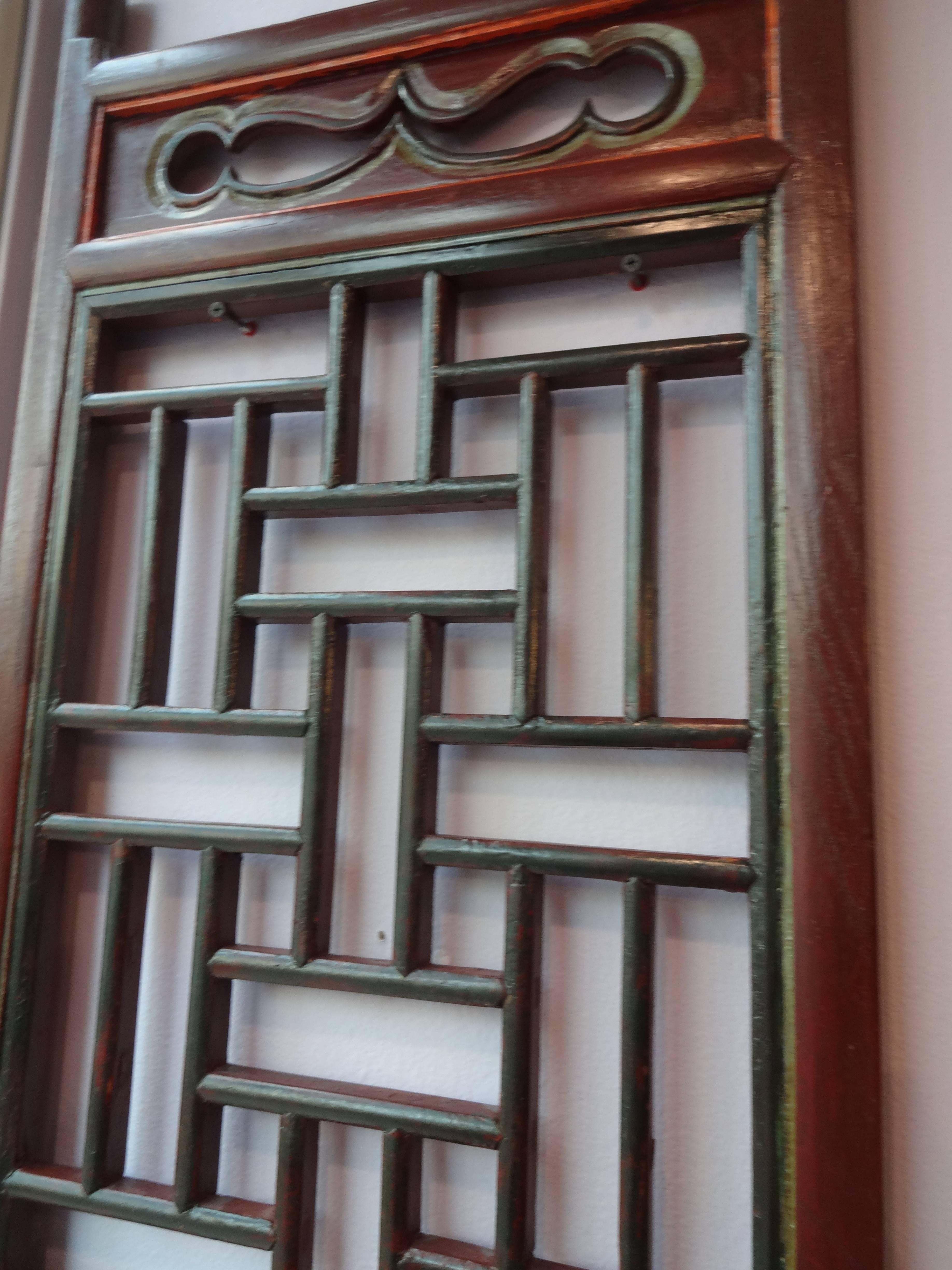 A pair of Chinese hand-carved elm wood screen doors, lacquered reddish brown with red, yellow and green design accents.