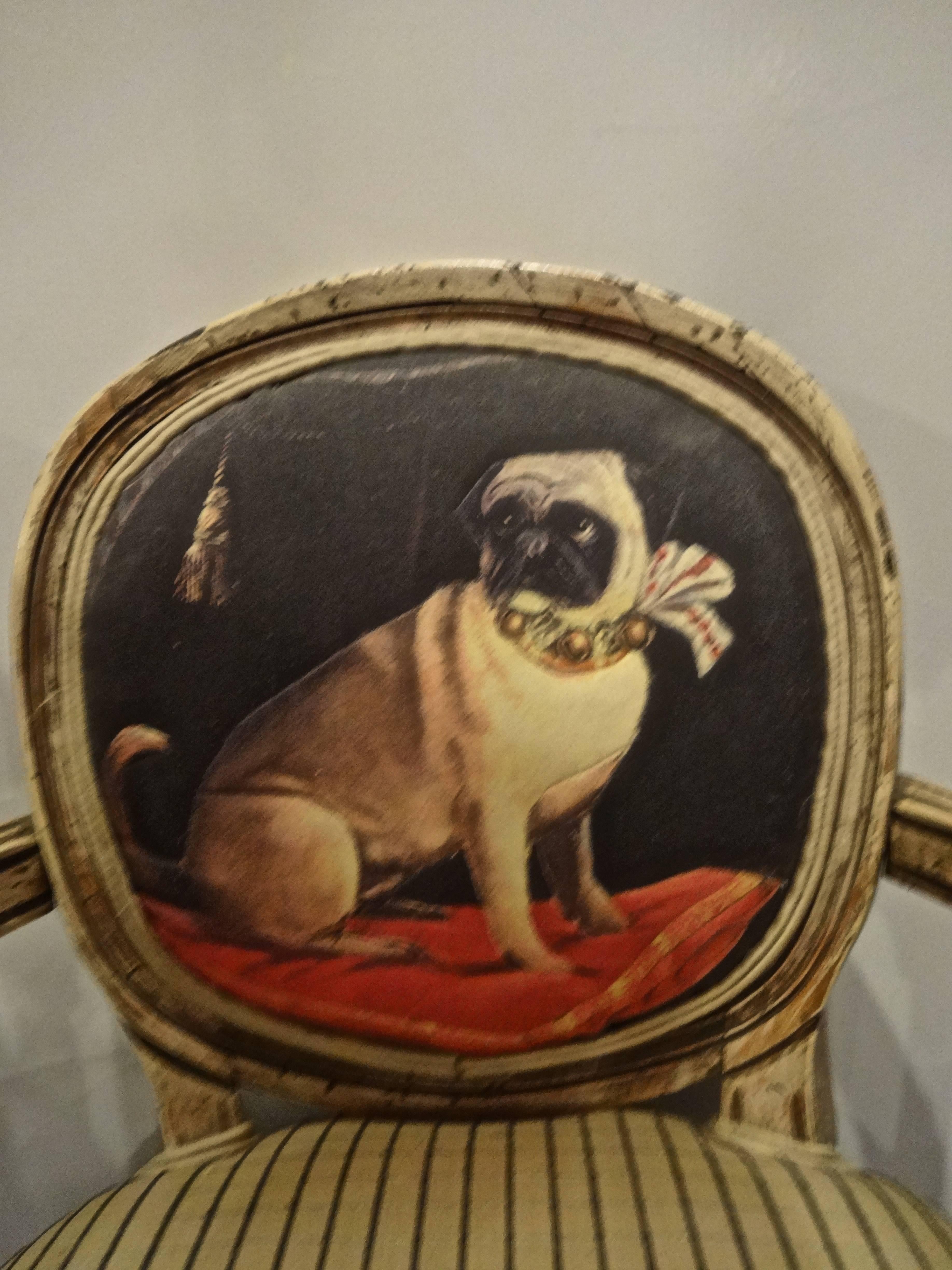 A small French Louis XVI style painted wood child's chair. The inside chair back is upholstered in an adorable printed cotton fabric depicting a pug dog seated on a red velvet cushion with a collar of bells and a plaid bow. Seat, armrests and back