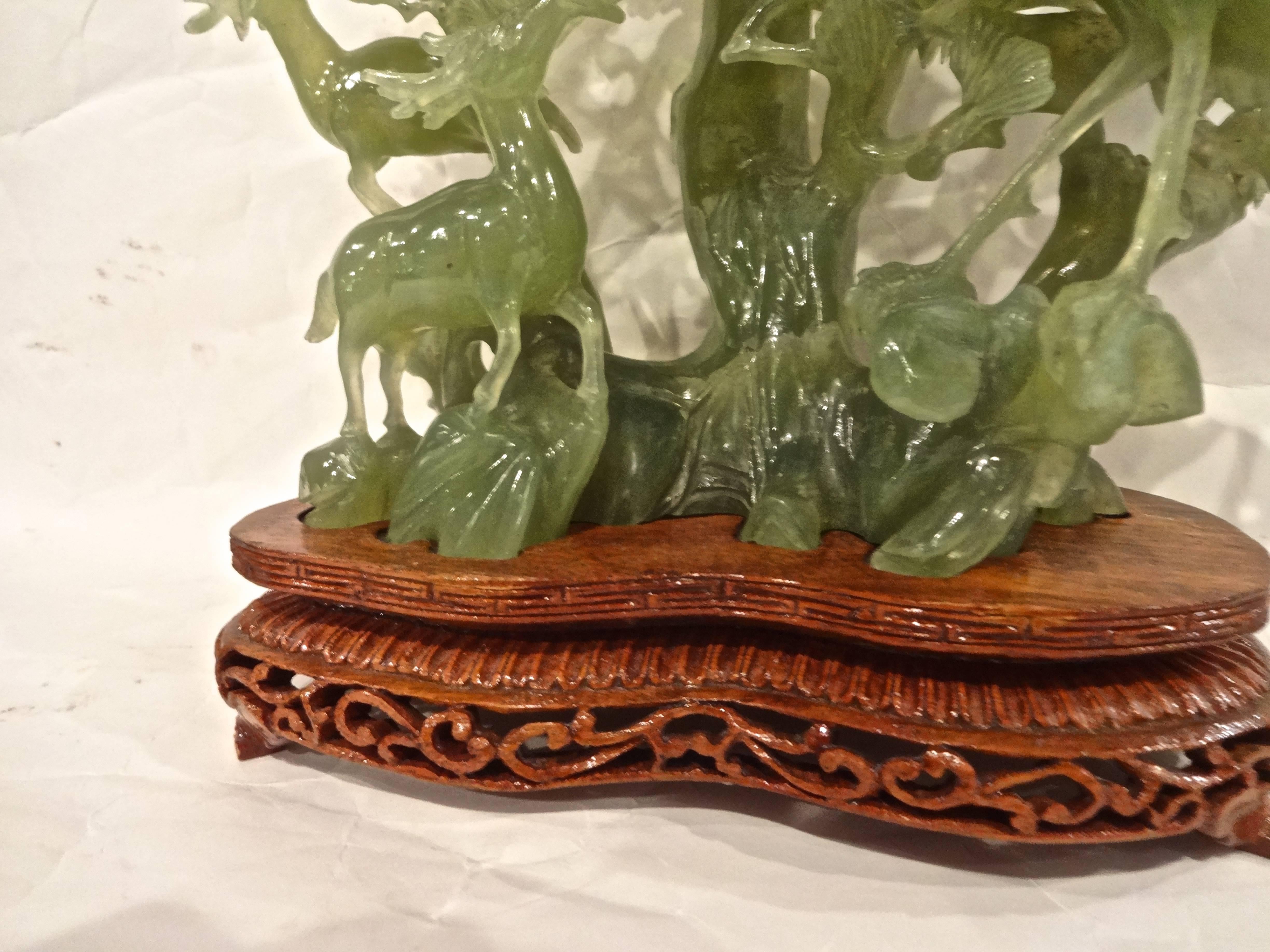 A Chinese jade carving of birds, fauna and deer on custom hand-carved stand.