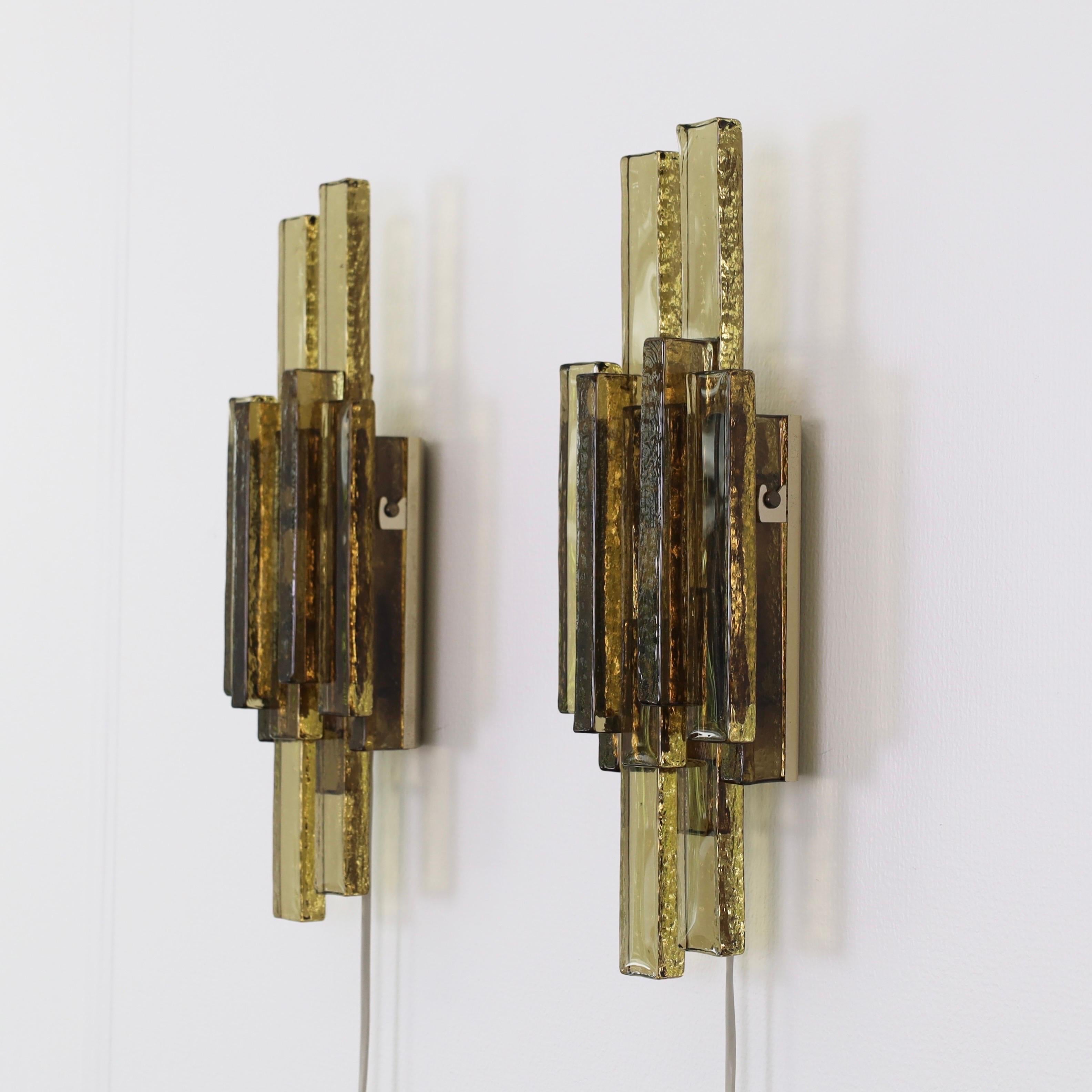 Pair of Smokey Glass Sconces made by Svend Aage Holm Sørensen in the 1960s. A rare set for a beautiful place.

* A pair (2) of sconces with a brass base and shades pieced together by thick textured smoke-coloured glass bricks
* Designer: Svend Aage