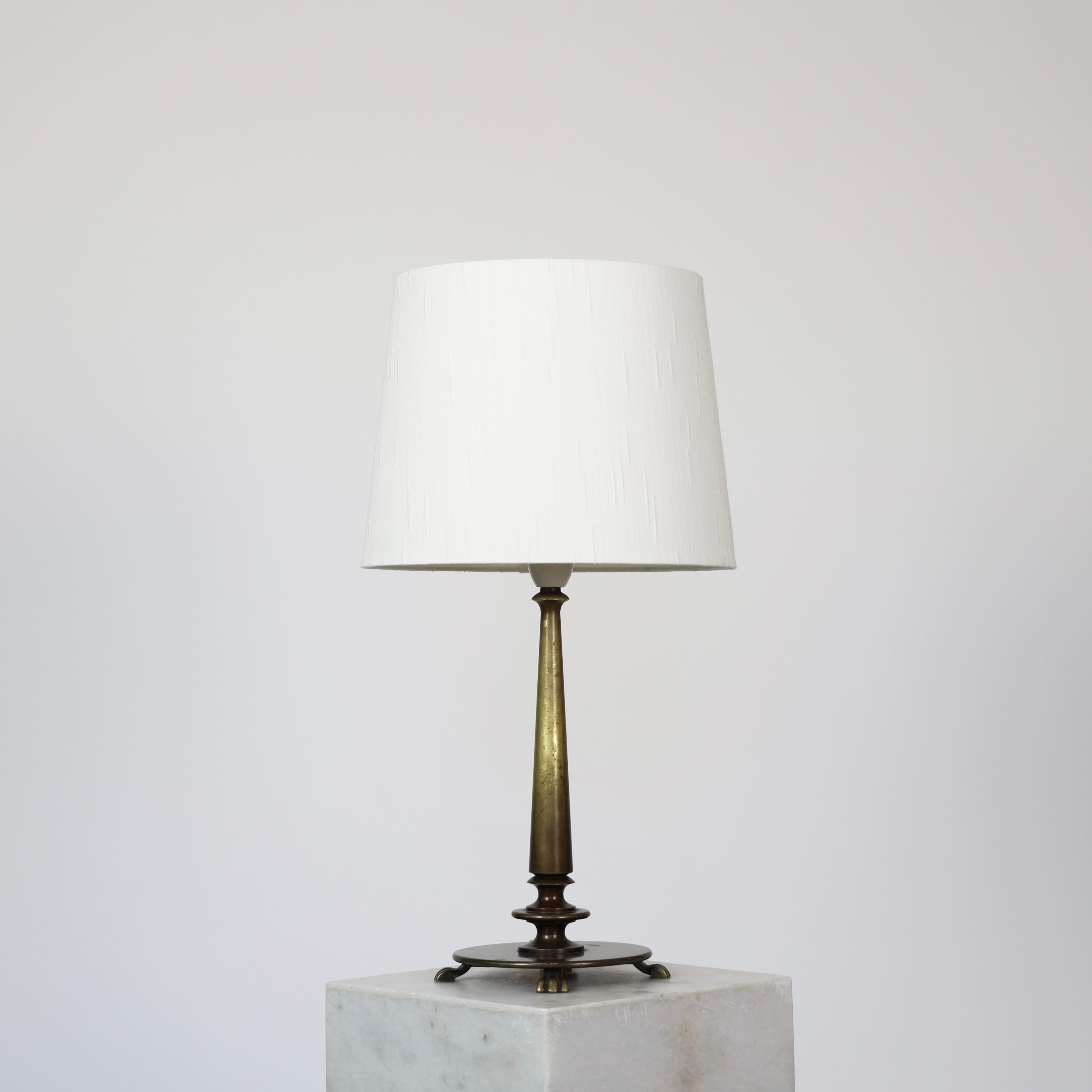Danish Art Deco Bronze Lamp from the 1930s. 
 
* Bronze lamp on round base with four legs, slim neck and a white shade. 
* Year: est. 1930s
* Condition: Good vintage condition. Bronze with lovely patina and few marks.* Dimensions, ex. shade (H x D):