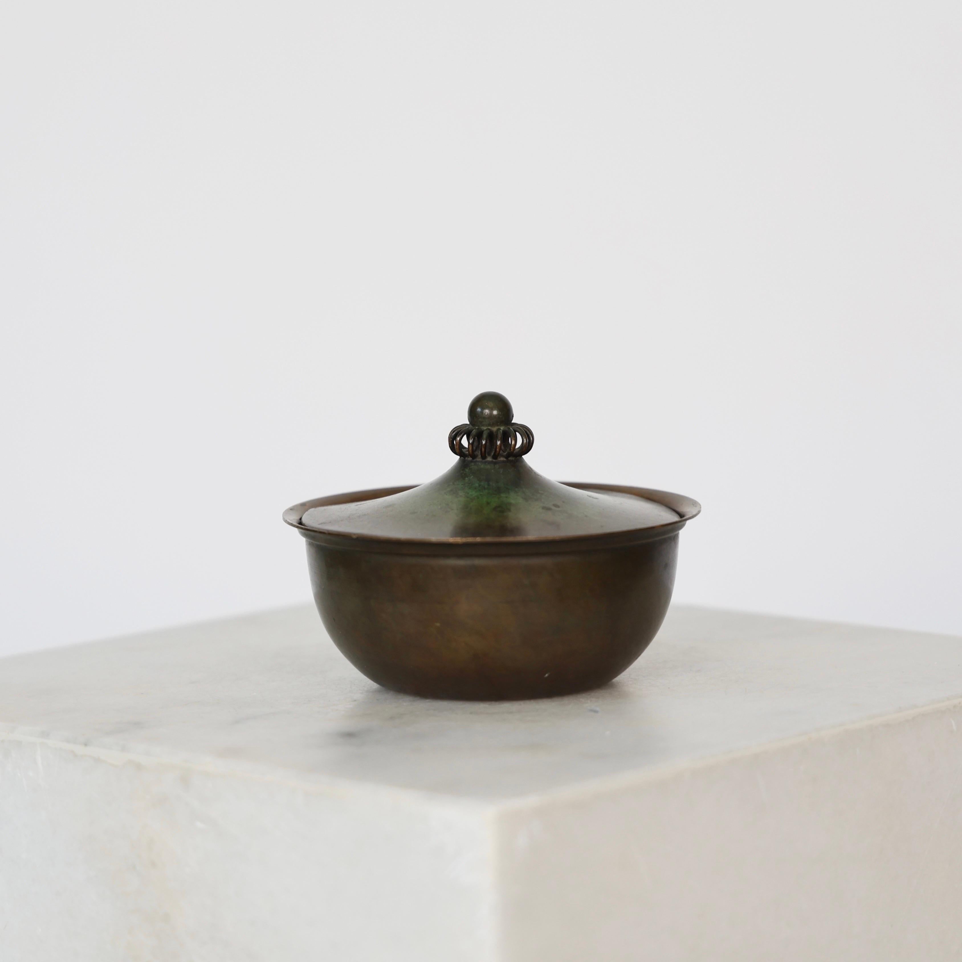 Round Light-Bronze Jar designed by Just Andersen in the 1930s. 

* Round bronze jar and lit with ornaments
* Designer: Just Andersen
* Model: LB 1615 (stamped 'Just’)
* Year: 1934
* Condition: Fair vintage condition. Makers engraving intact. It has