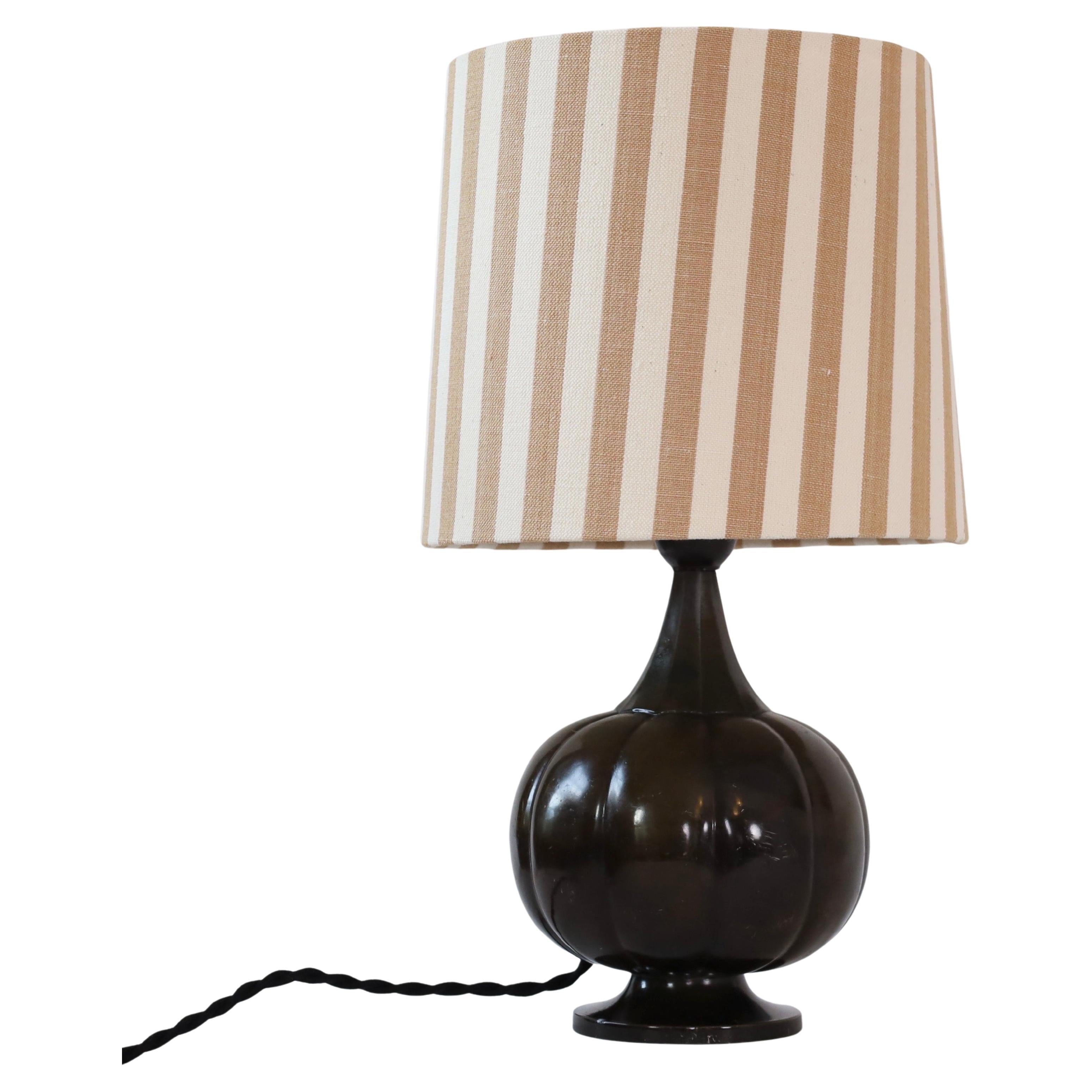 Lampada da tavolo Diskometal a forma di zucca disegnata da Just Andersen alla fine degli anni Venti. Una bella lampada per una bella casa.

* Lampada da tavolo discoidale a forma di zucca con paralume in tessuto a righe color cognac.
* Stile: 1273