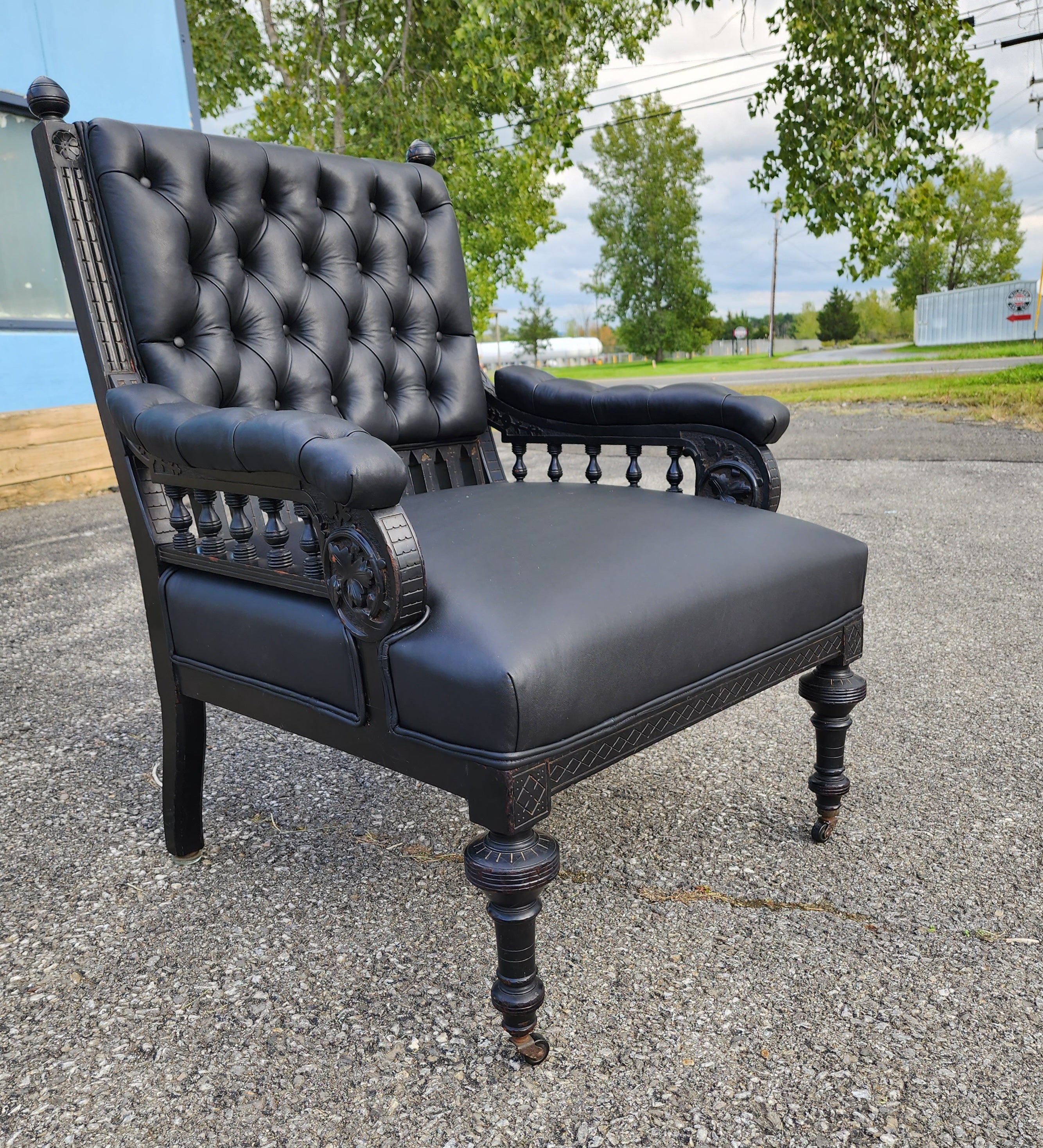 A wonderful and sexy piece. Newly upholstered in supple glove leather and retaining its original patinaed carved wooden ebonized surfaces. The front feet retain their original casters and back with original glass slides. The carving is of