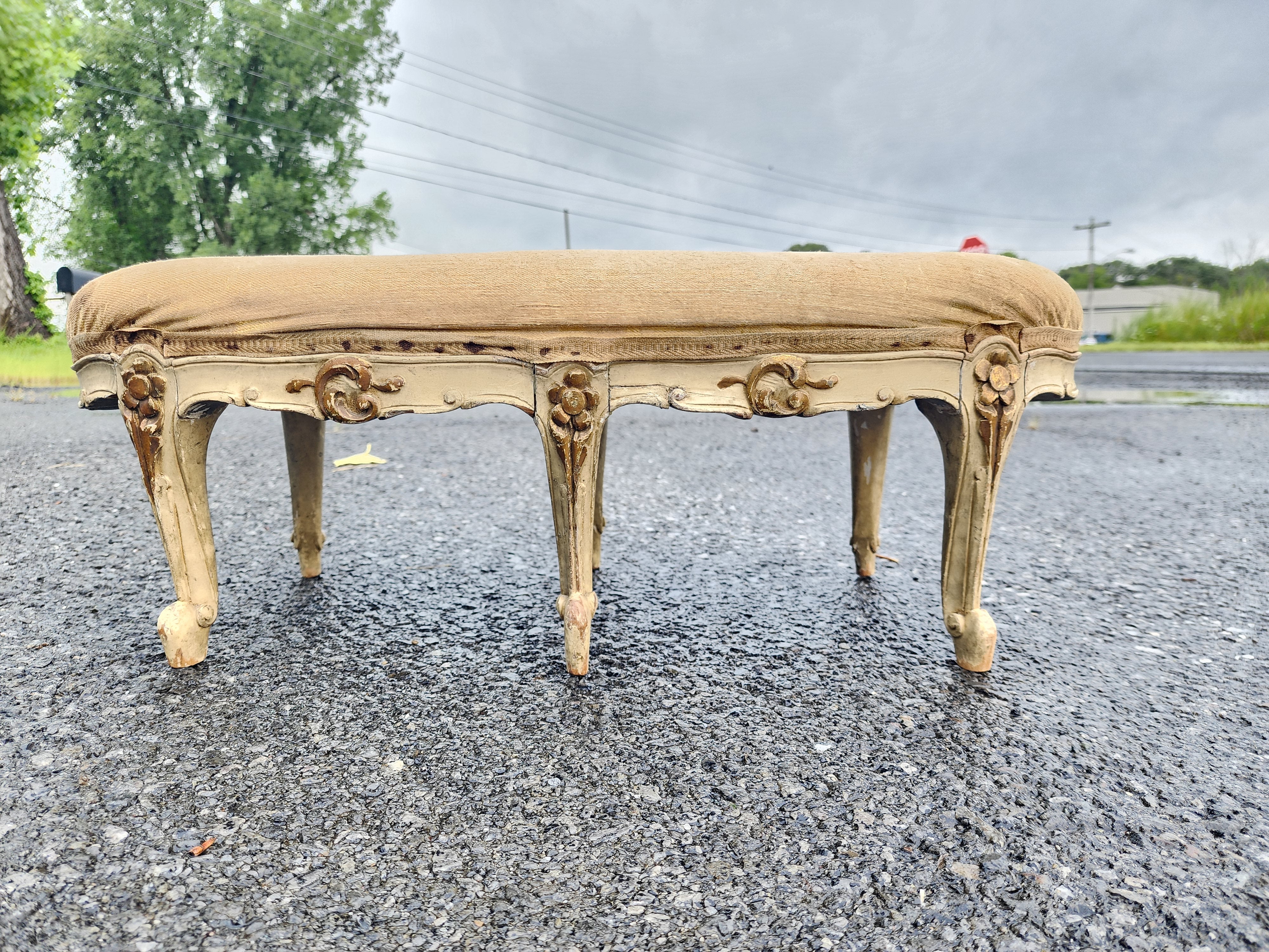 This is an extremely handsome French Rococo Revival footstool. Unusual shape and size. Mid-19th Century likely France retaining the original Gray undercoat with cream exterior and gold gilding. Also retaining the original upholstery and surface.
We