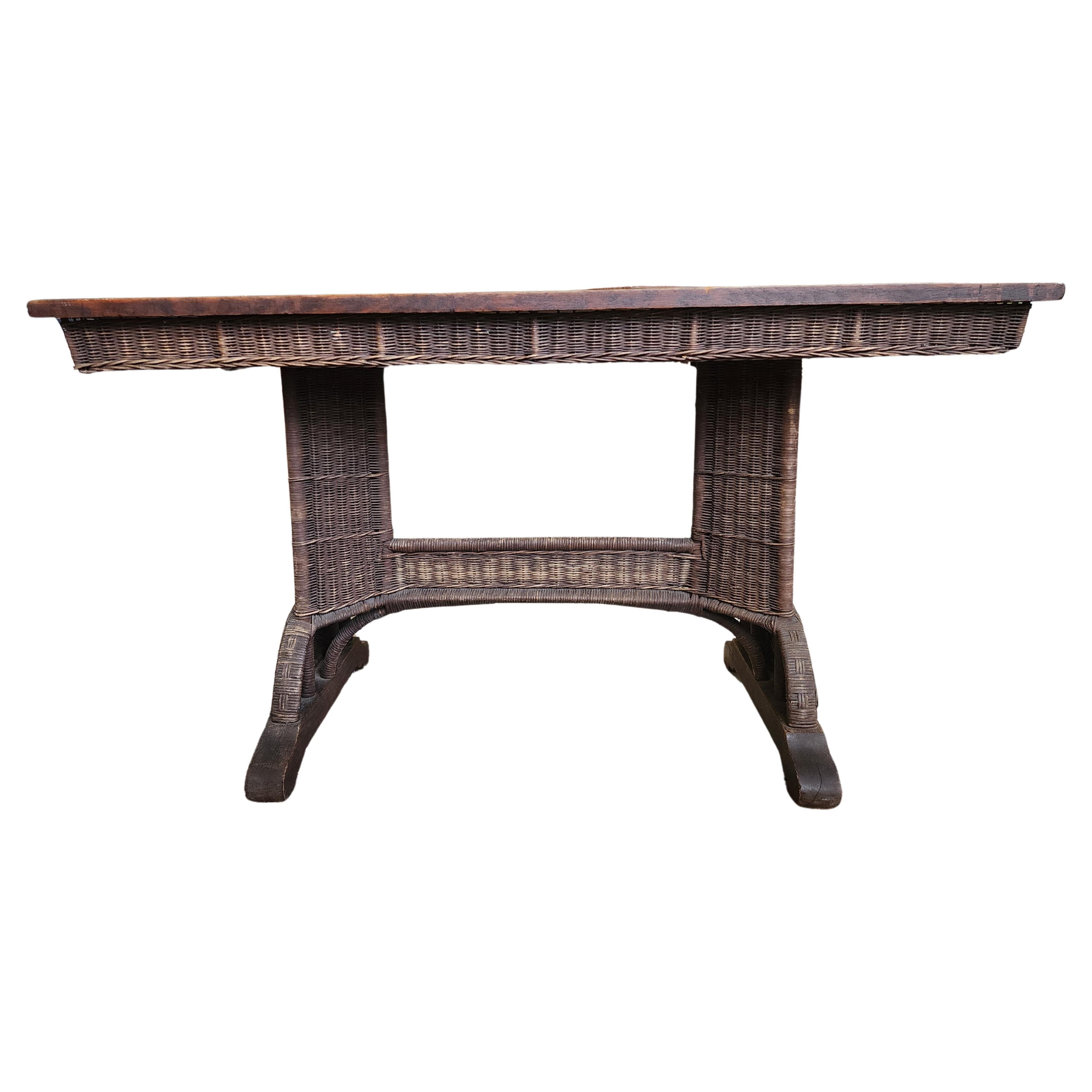 Heywood Wakefield library table. With quarter sawn, oak top and woven wicker pedestal legs, apron, and stretcher. This wicker table drew on the Aesthetic Movement and Japanese influences; simpler designs arose in the wake of the Arts and Crafts