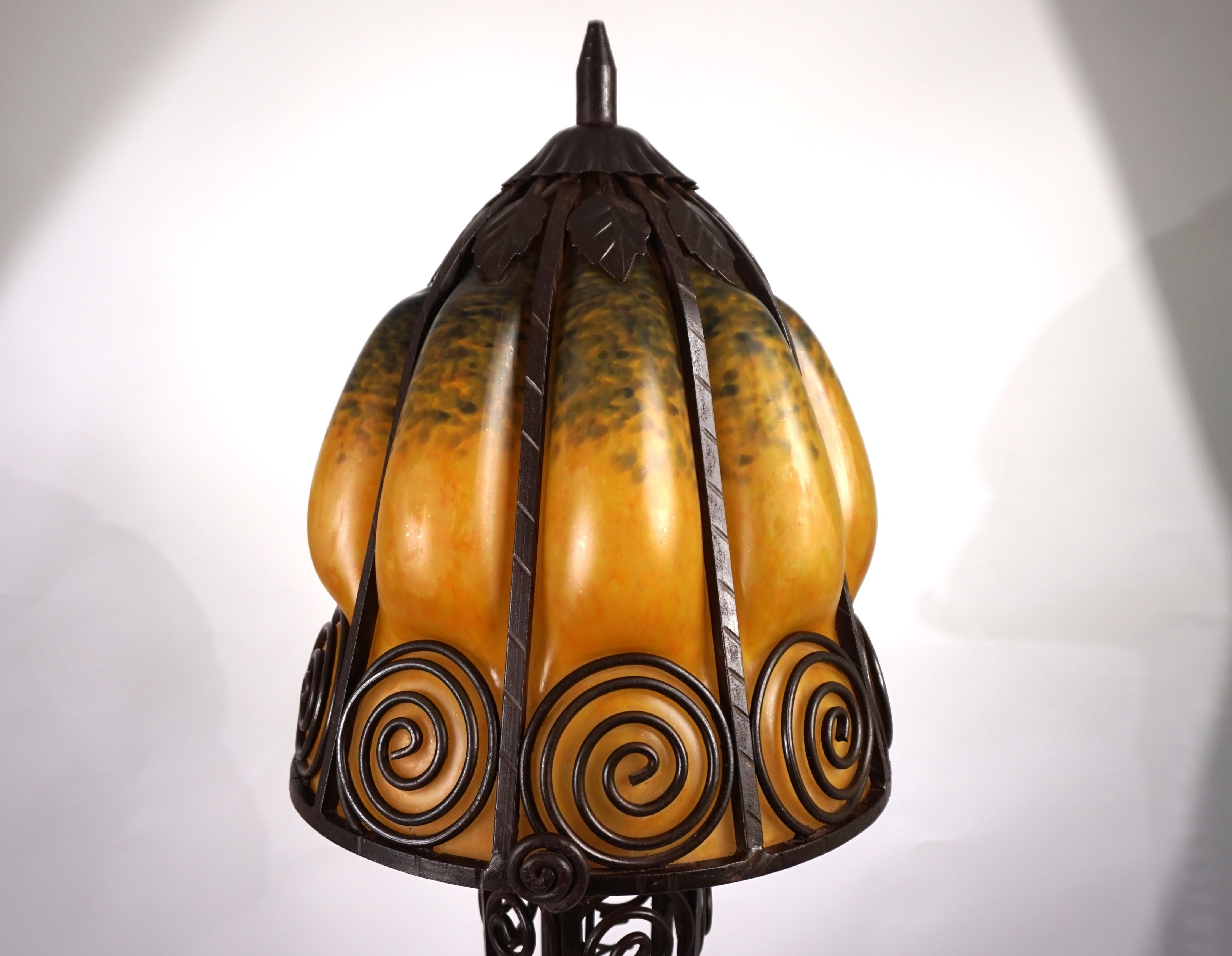 Questa solida lampada da terra in ferro battuto è in ottime condizioni con una bella patina. La struttura in ferro, con ornamenti di foglie e fiori che si ripetono sulla base e sul paralume, è di ottima fattura e fornisce all'intera lampada una base