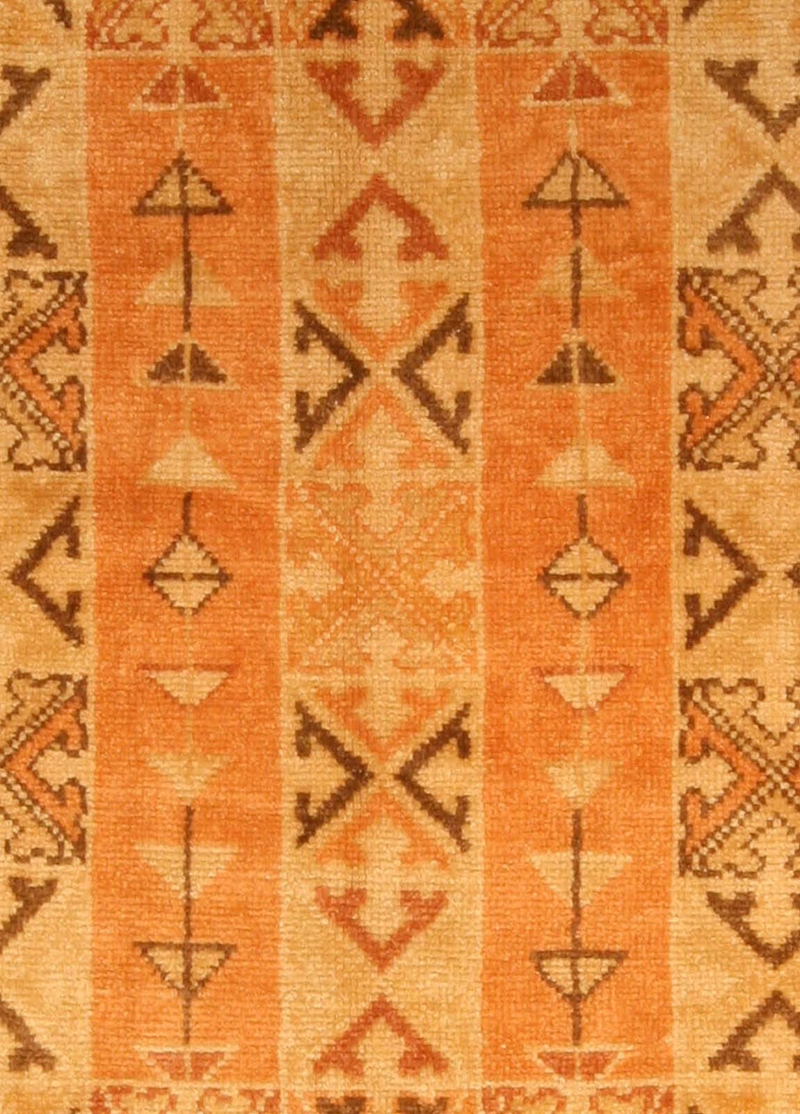 A mid-20th century tile carpet from Morocco, the tiles containing triangles and tilted shapes in shades of rust, beige and brown within a rust linked triangle and abstract flowerhead border.